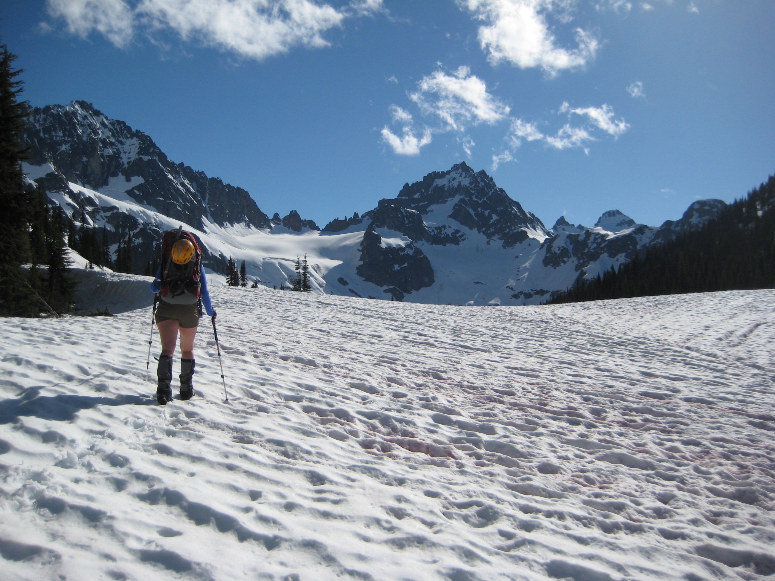 mountain climber booting up snow filled basin below Kitling Pass with Kimtah Peak on Ragged Ridge in the background