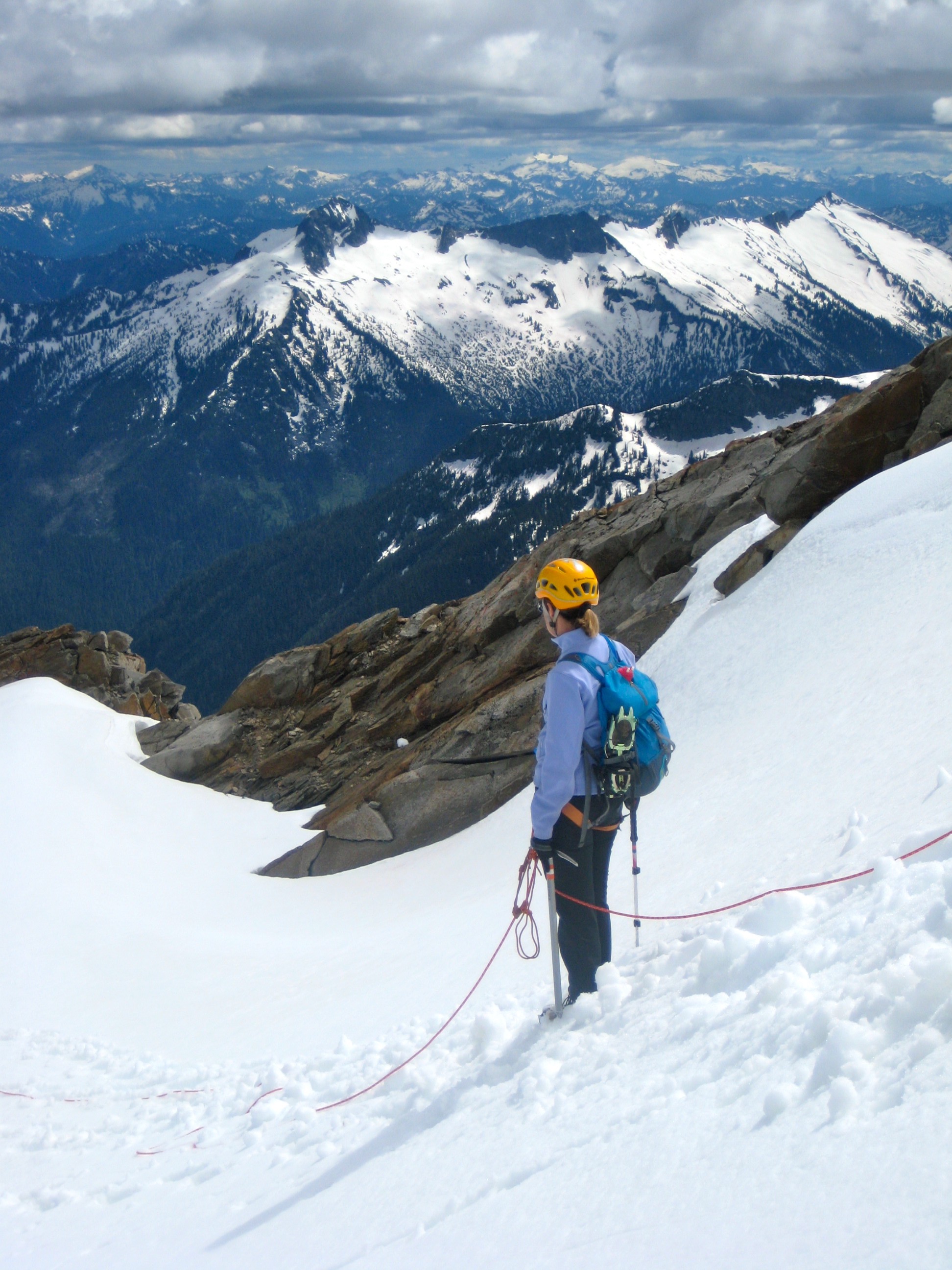 roped mountain climber looking across valley at Mt David in the North Cascades with high, dark clouds