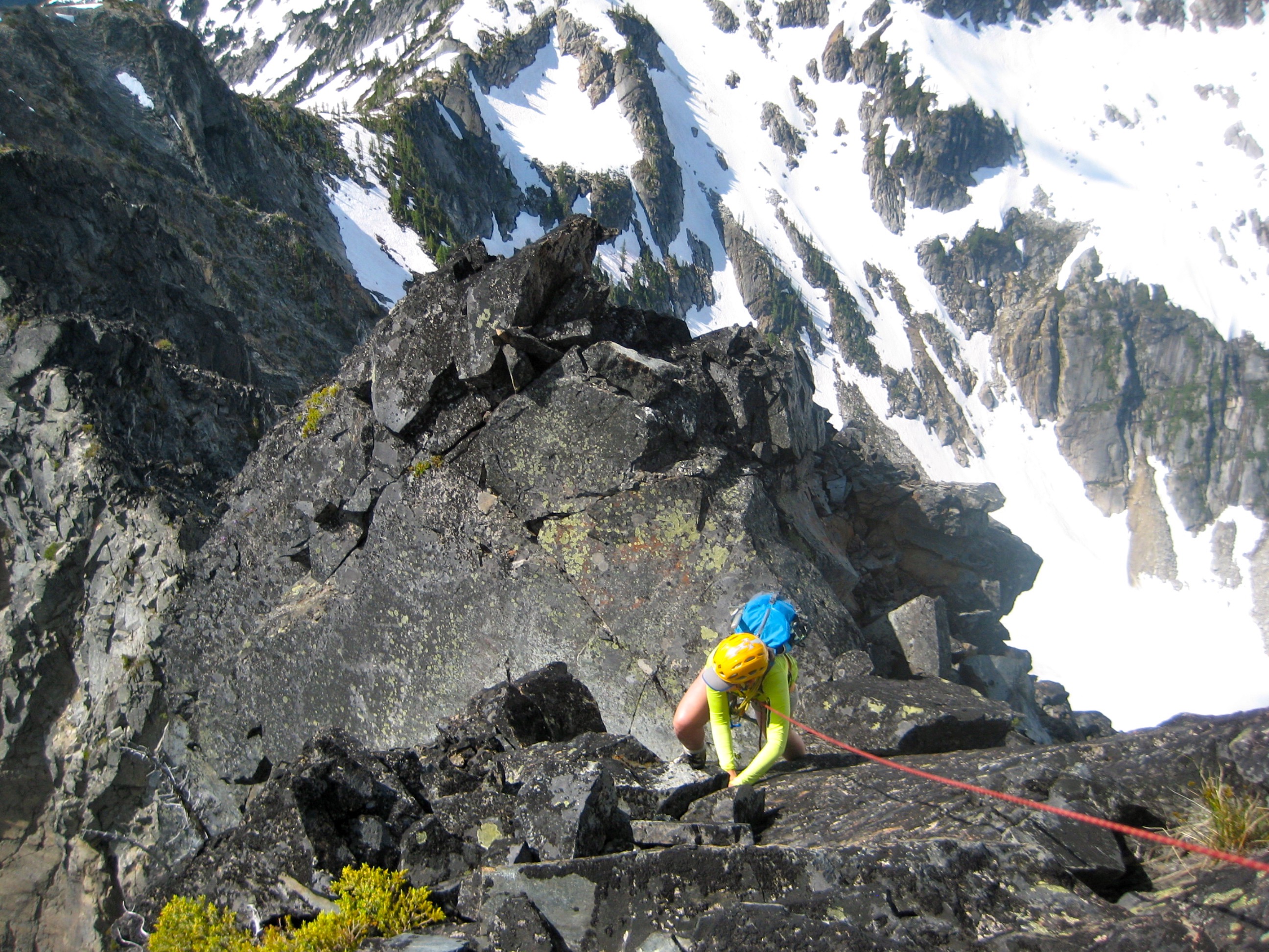looking down on roped mountain climber scrambling steep rocky south ridge of Anges Mountain in the Glacier Peak Wilderness