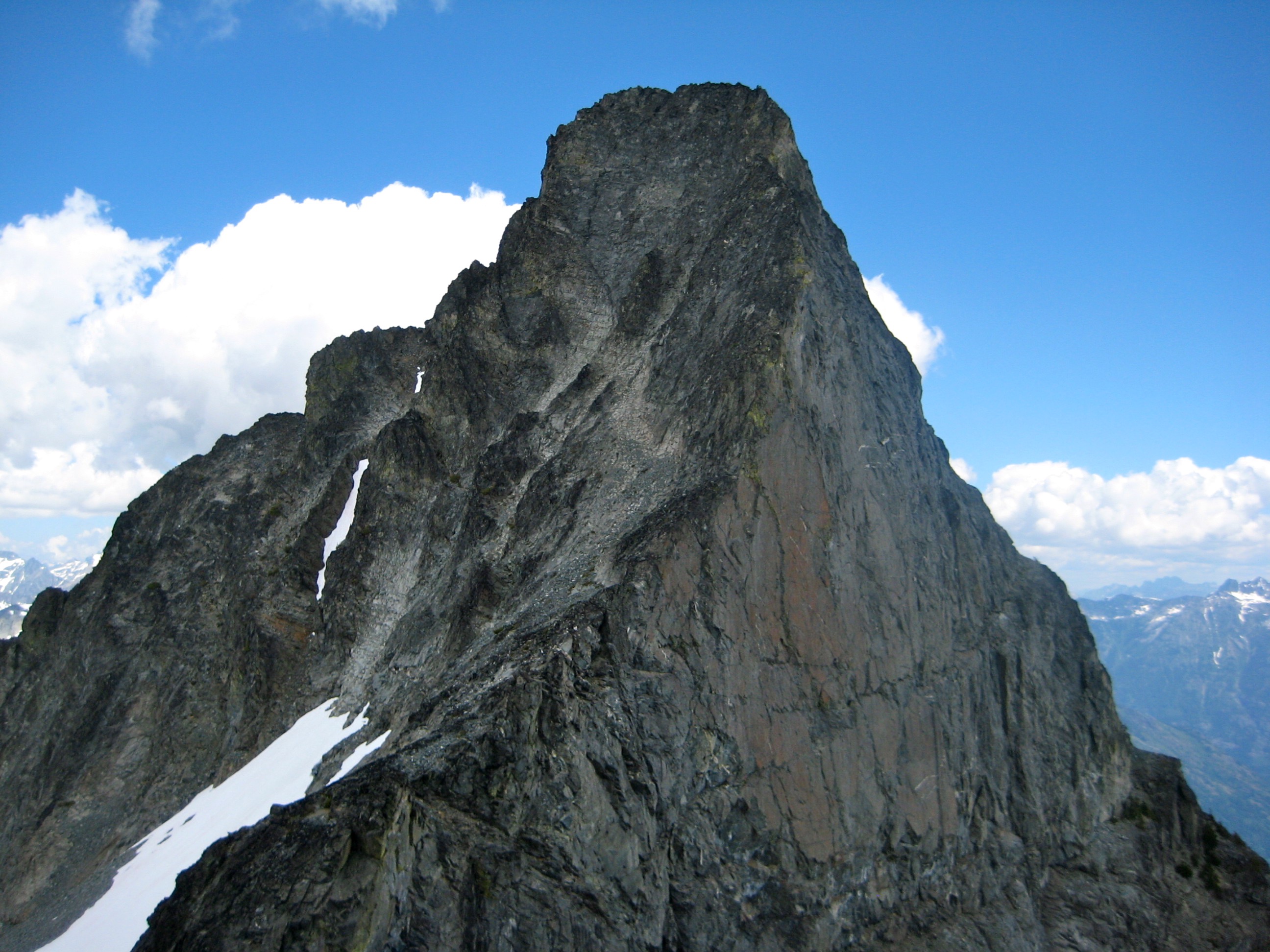 The steep, blocky summit of Agnes Mountain stands against a blue sky in the Glacier Peak WIlderness