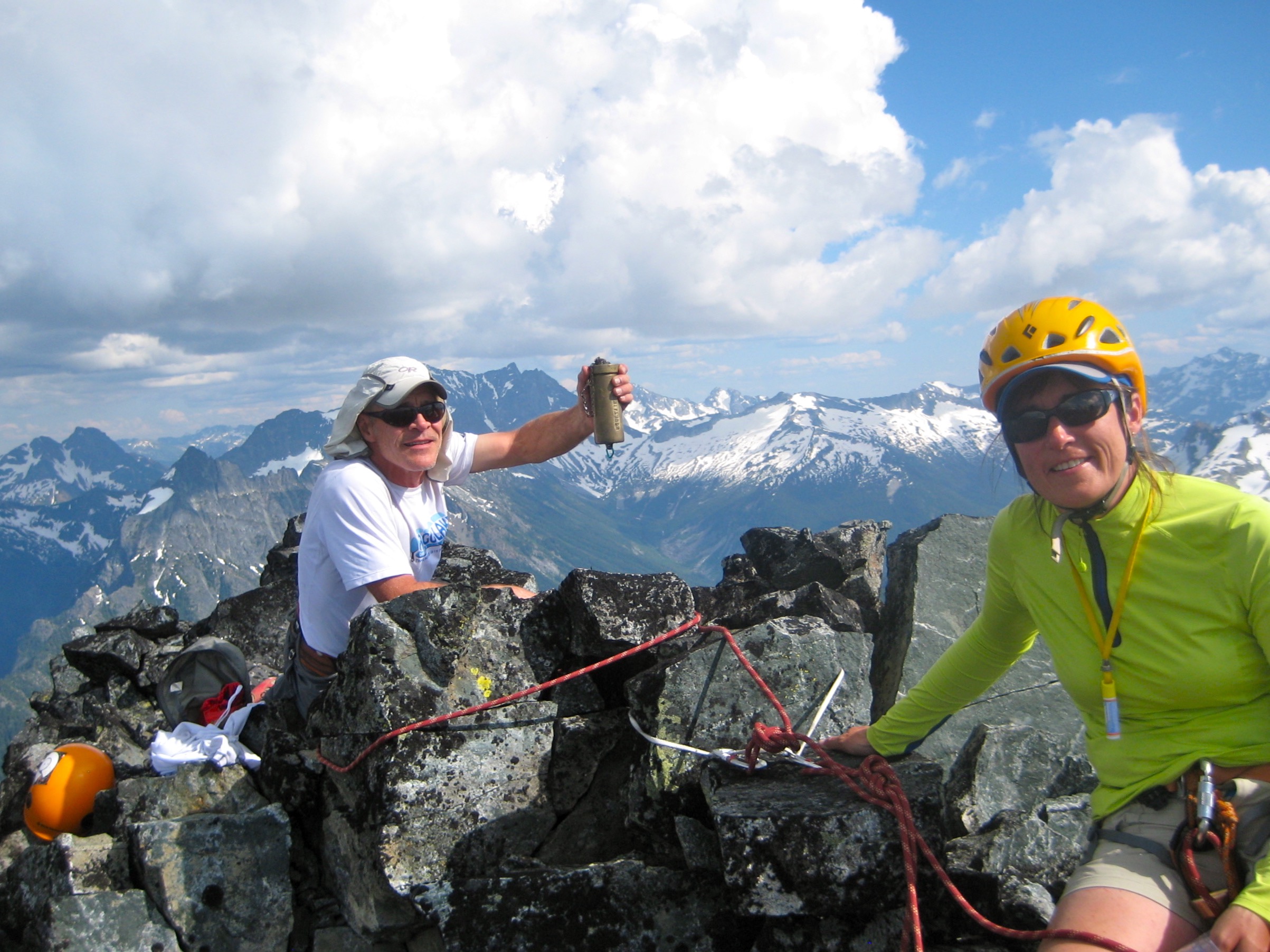 mountain climbers celebrating in the boulders on the summit of Agnes Mountain with the Glacier Peak Wilderness in the background