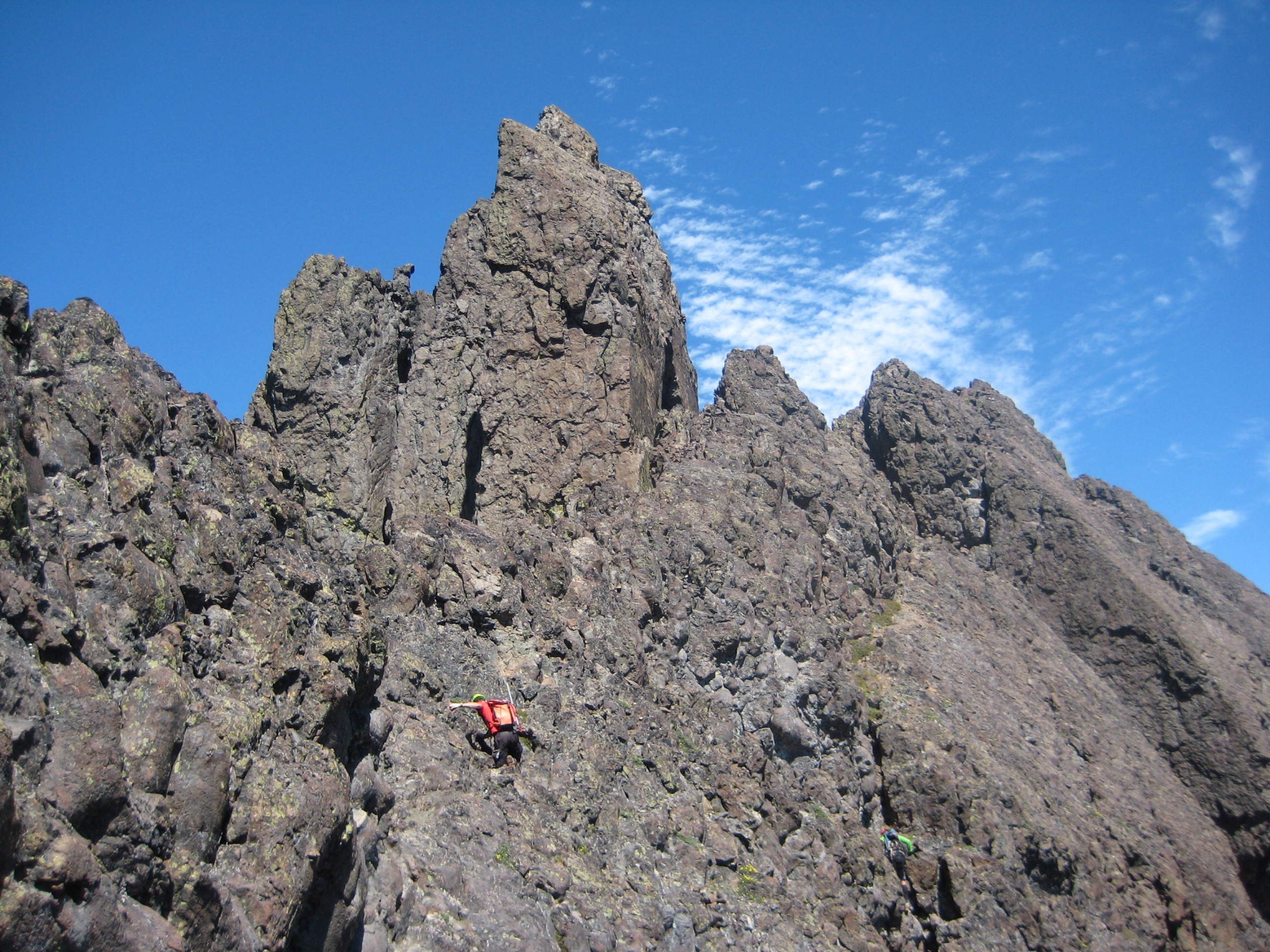 mountain climber scrambling rocky summit block of Mt Constance Outer Peak in the Olympic National Park