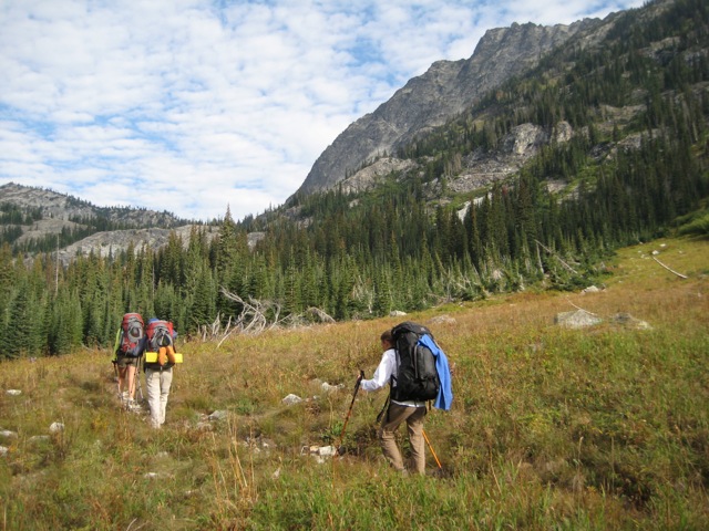 hikers on trail heading through a meadow with fall colors on the Rainbow Ridge Loop in the Stehekin Mountains
