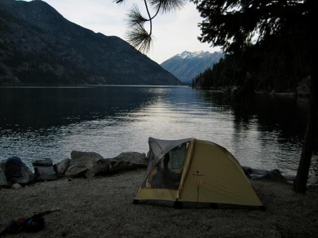 A yellow tent sits next to Lake Chelan with a view of the mountains
