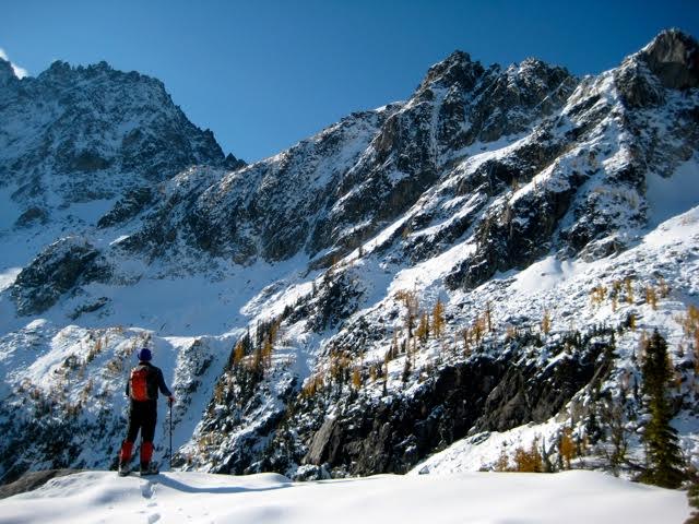 A mountain climber gazes at a snow-dusted rocky ridge leading from Goat Pass to Jackaroo Peak