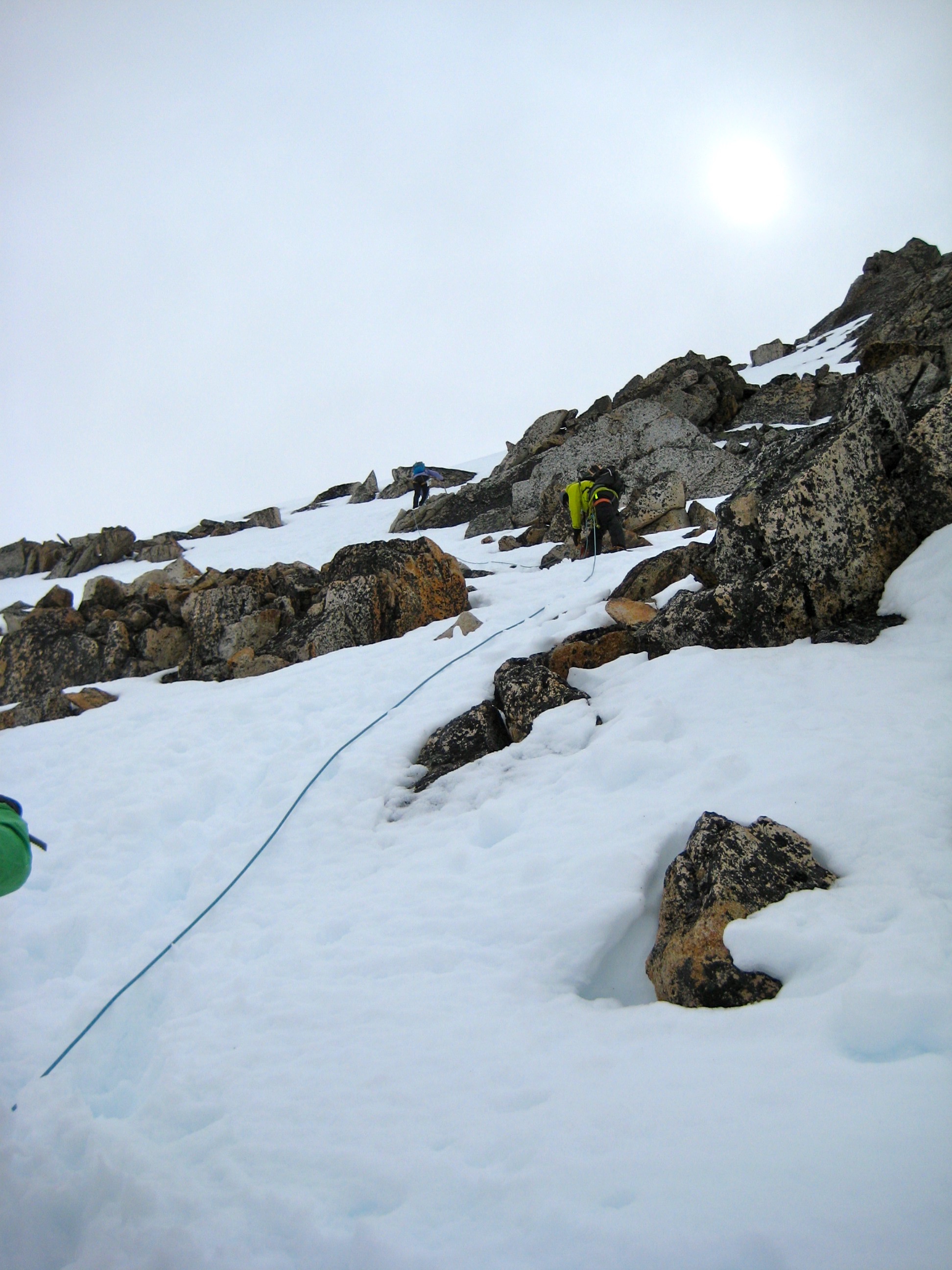 looking up at roped mountain climbers booting up patchy snow slope leading to the summit of Silver Star Mountain