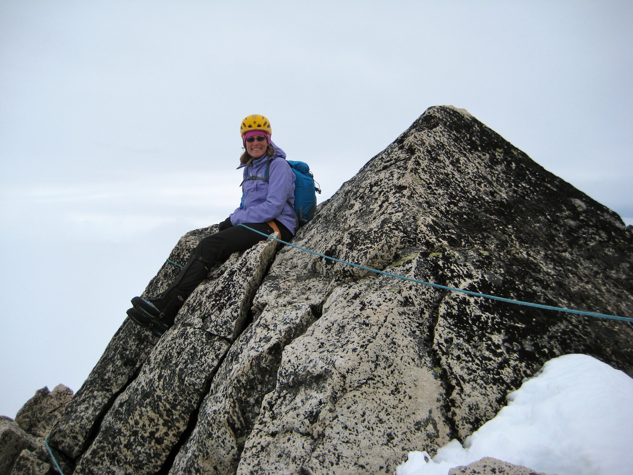roped mountain climber sitting on the rocky summit horn of Silver Star Mountain in the Mazama Mountains belaying