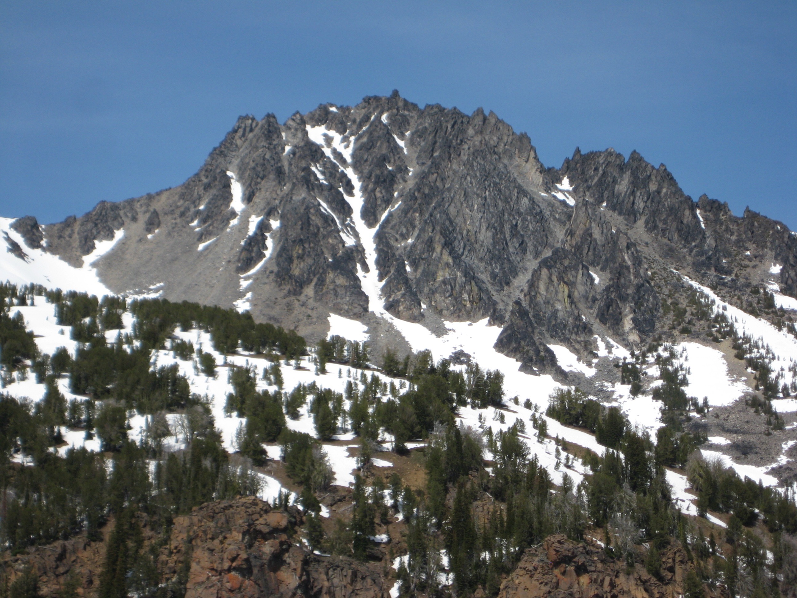 The broad face of Cashmere Mountain stands above a slope with patchy snow