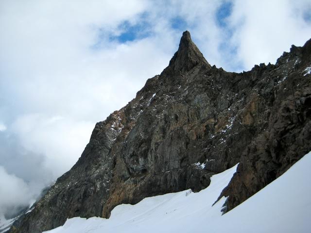 A slender rock pinnacle of Foley Peak towers over a snowfield in the Cheam Range