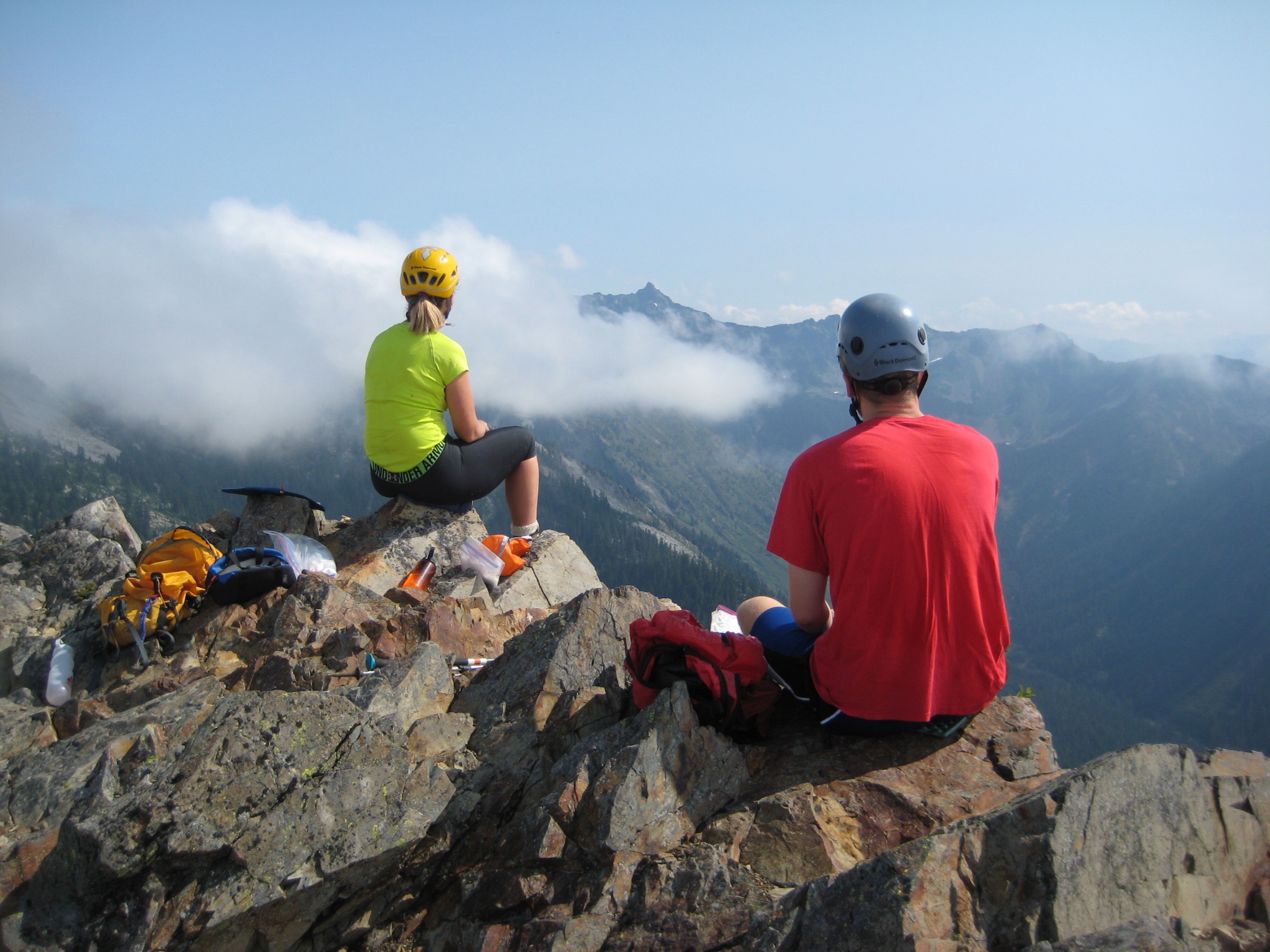 Two mountain climbers sit on the rocky summit of Kendall Peak in the Snoqualmie Mountains
