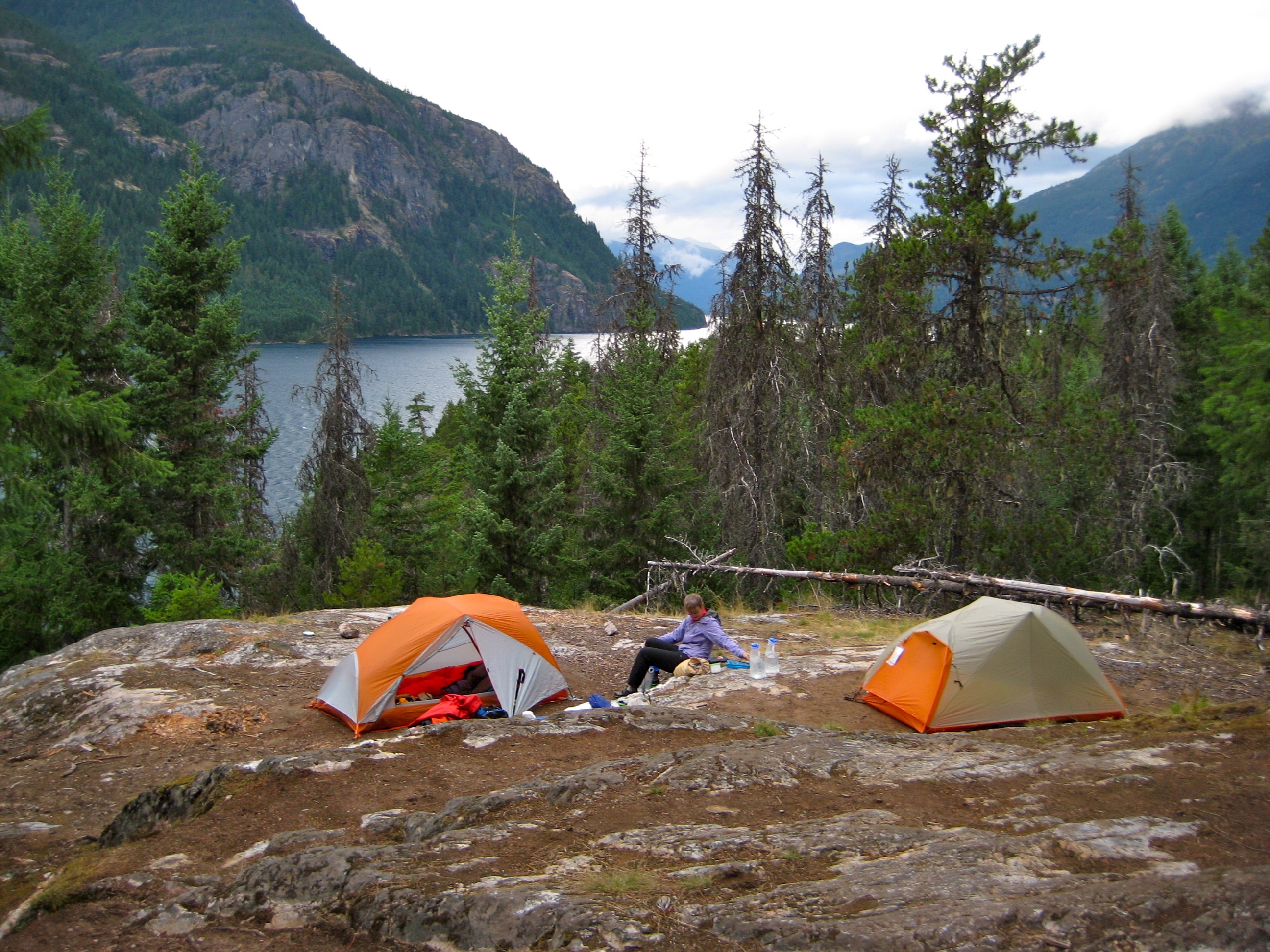 Hiker's camp on slab with grass at Devils Junction overlooking Ross Lake at the start of the Jack Mountain High Circuit