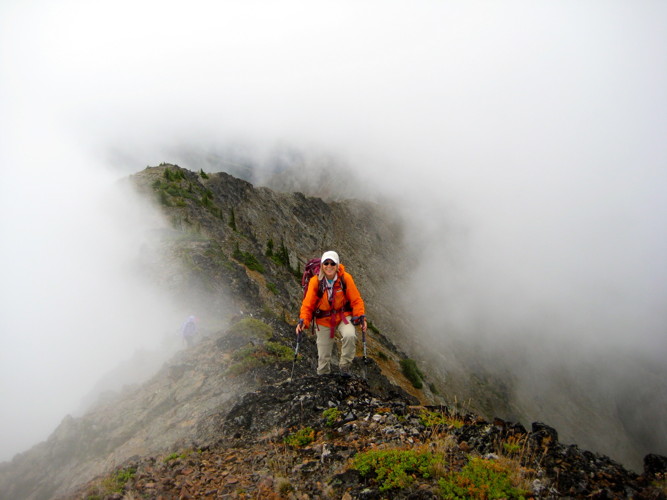 hiker on Daemon Peak rocky ridge near the summit of Daemon Peak in the Upper Skagit Mountains surrounded by fog
