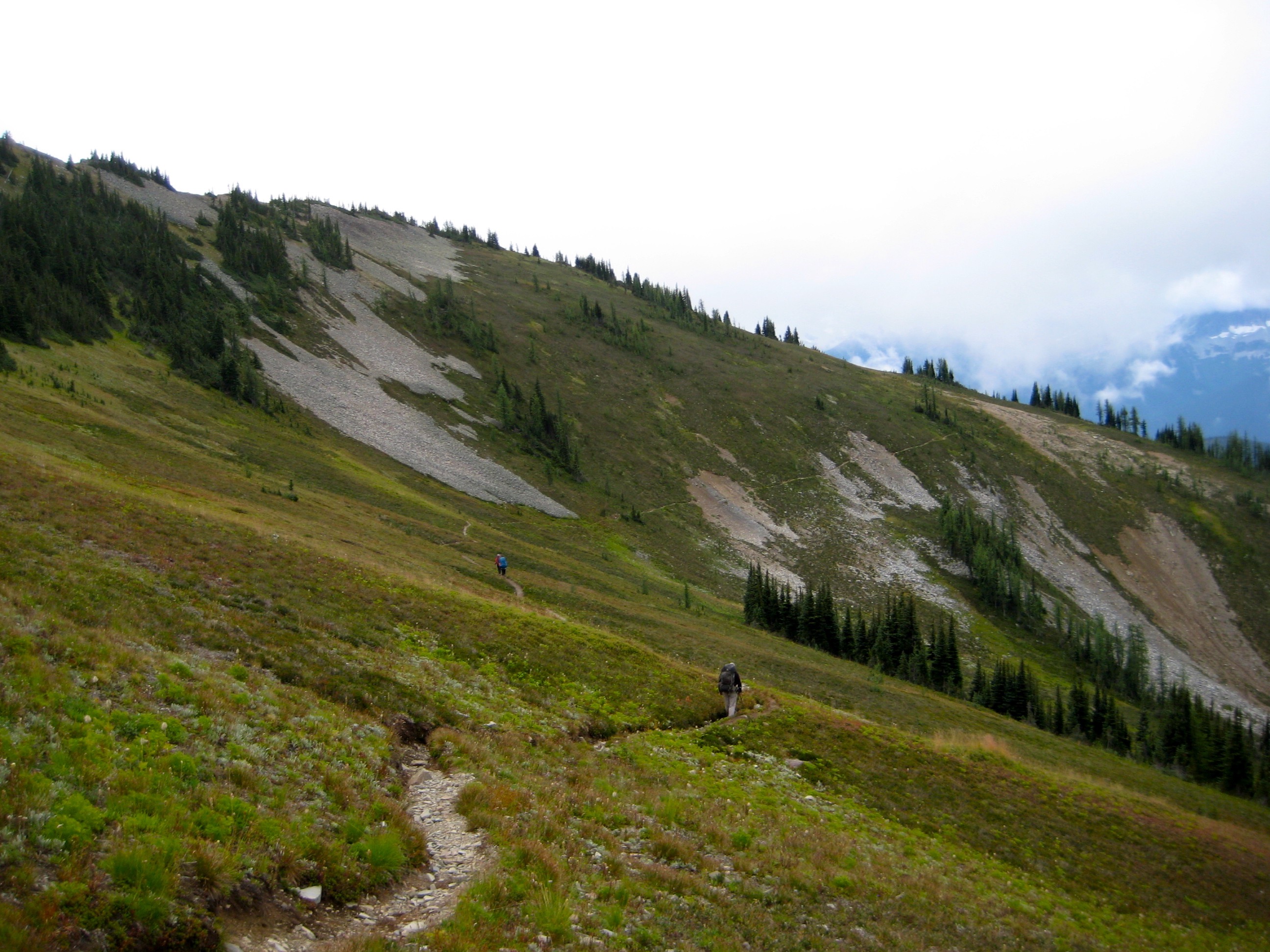 backpackers hiking the Jack Mountain High Circuit trail around the Head Of Devils Creek Valley filled with heather and low grass