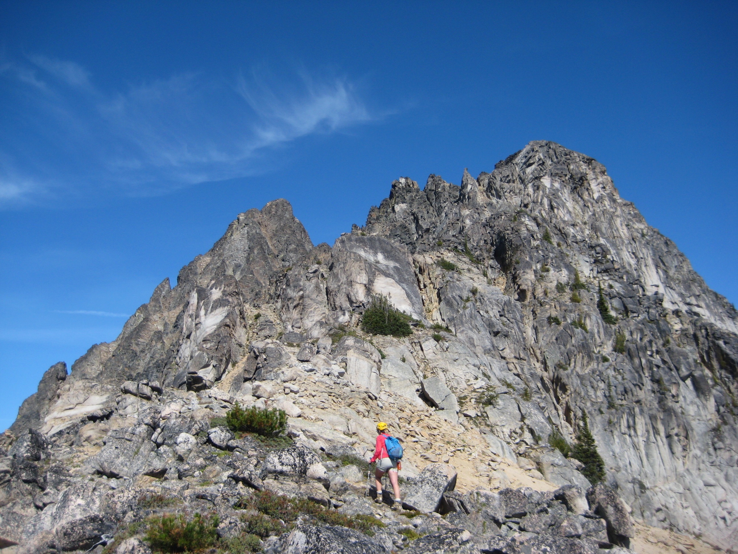 A mountain climber scrambles up a steep gray face on Azurite Peak