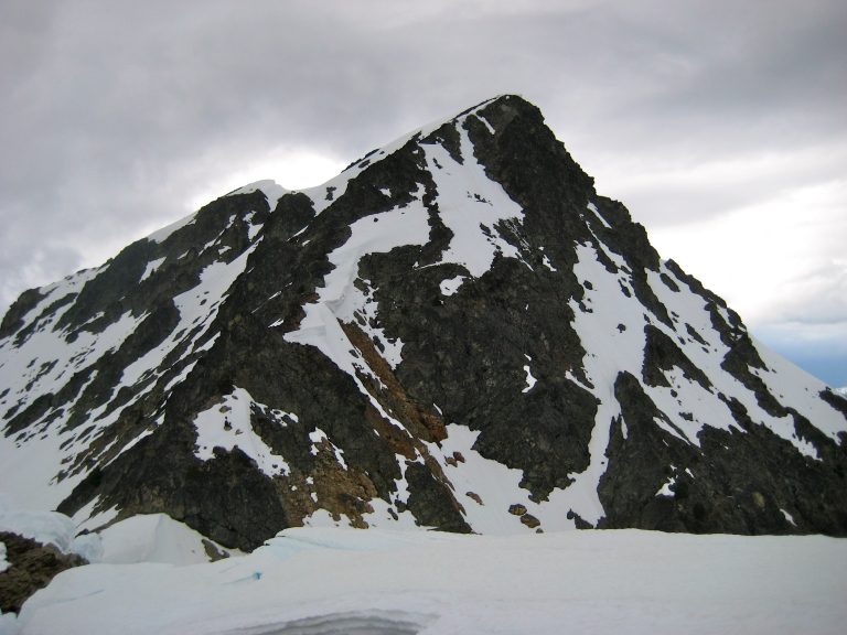 The pyramidal summit of Kitling Peak rises above a snowy ridge