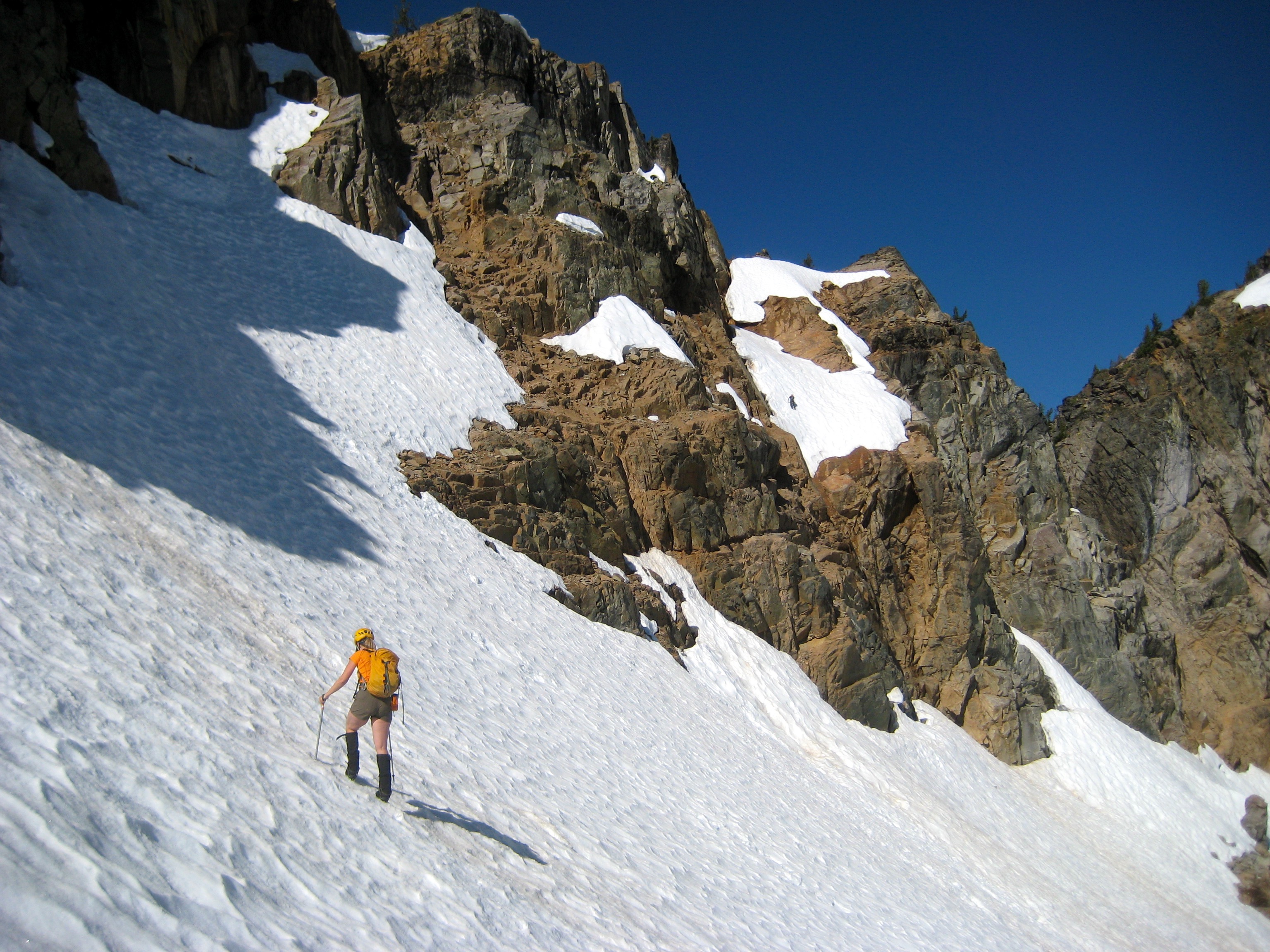 mountain climber booting up steep snow field on the shoulder of Corteo Peak in the Ragged Ridge Mountains in North Cascades National Park