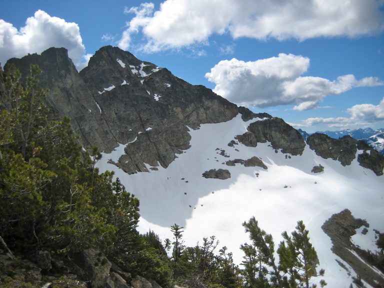 A snow basin and rocky ridge lead up to the summit of Corteo Peak in the Ragged Ridge Mountains in North Cascades National Park