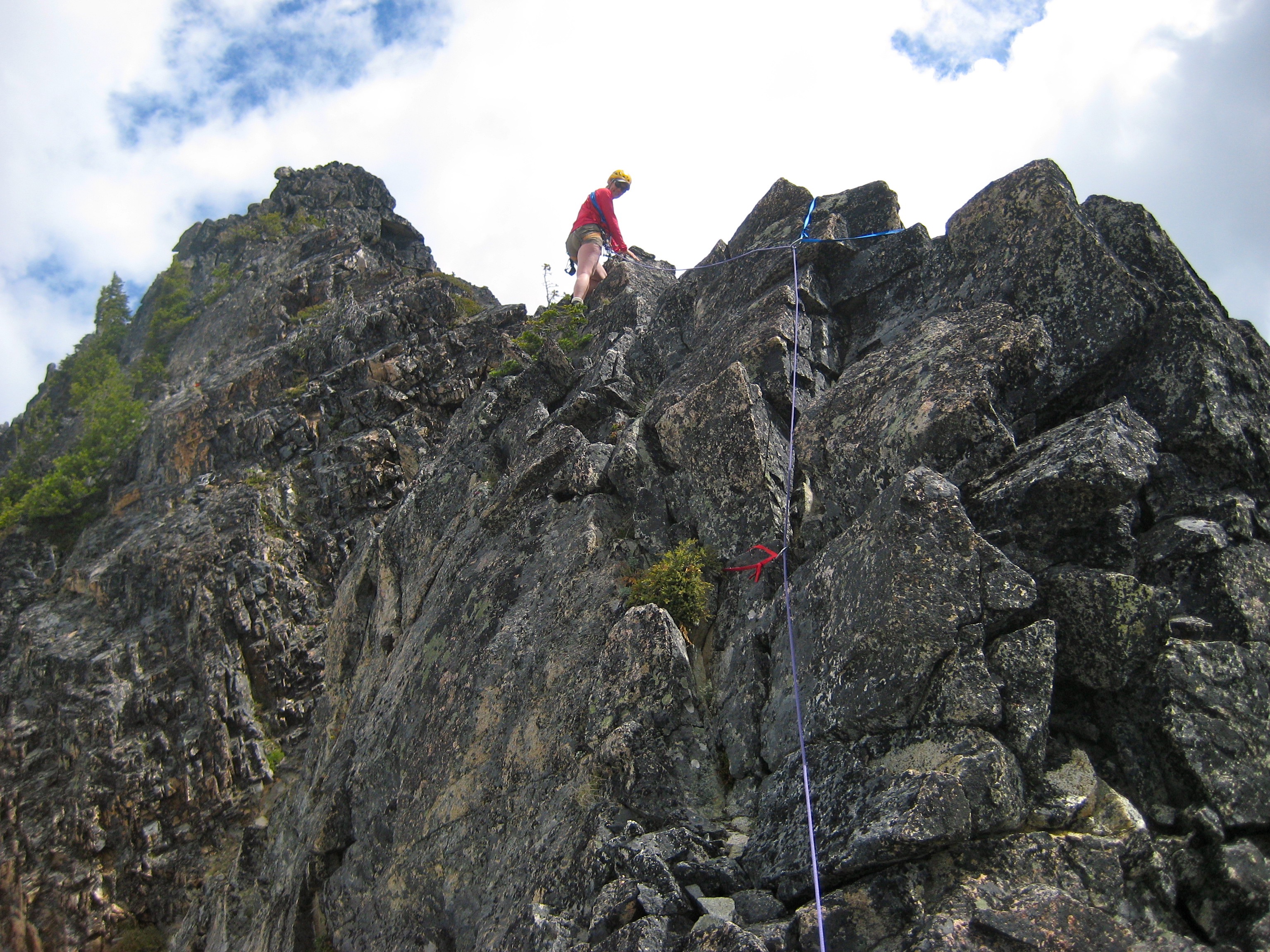 looking up at roped mountain climber on the rocky, SW Ridge of Corteo Peak in the Ragged Ridge Mountains in North Cascades National Park