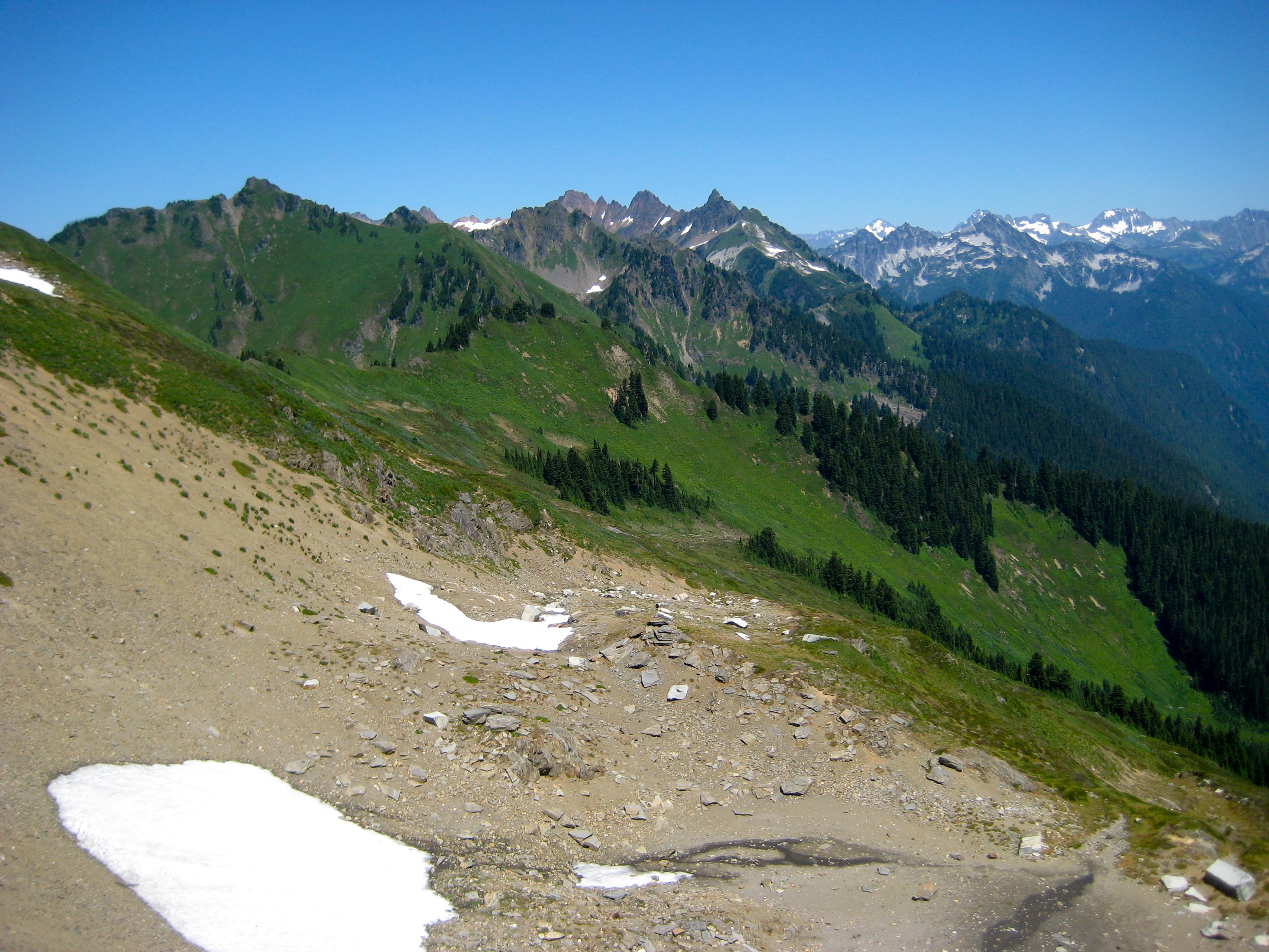 mountain view with green fields and linguring snow fields in the Glacier Peak Wilderness