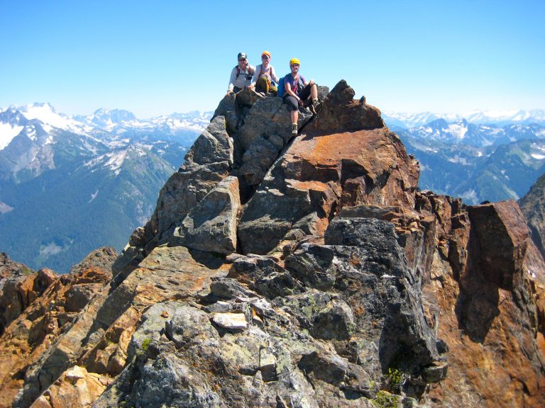 Mountain climbers wave from the red summit of Mt Misch in the Glacier Peak Wilderness