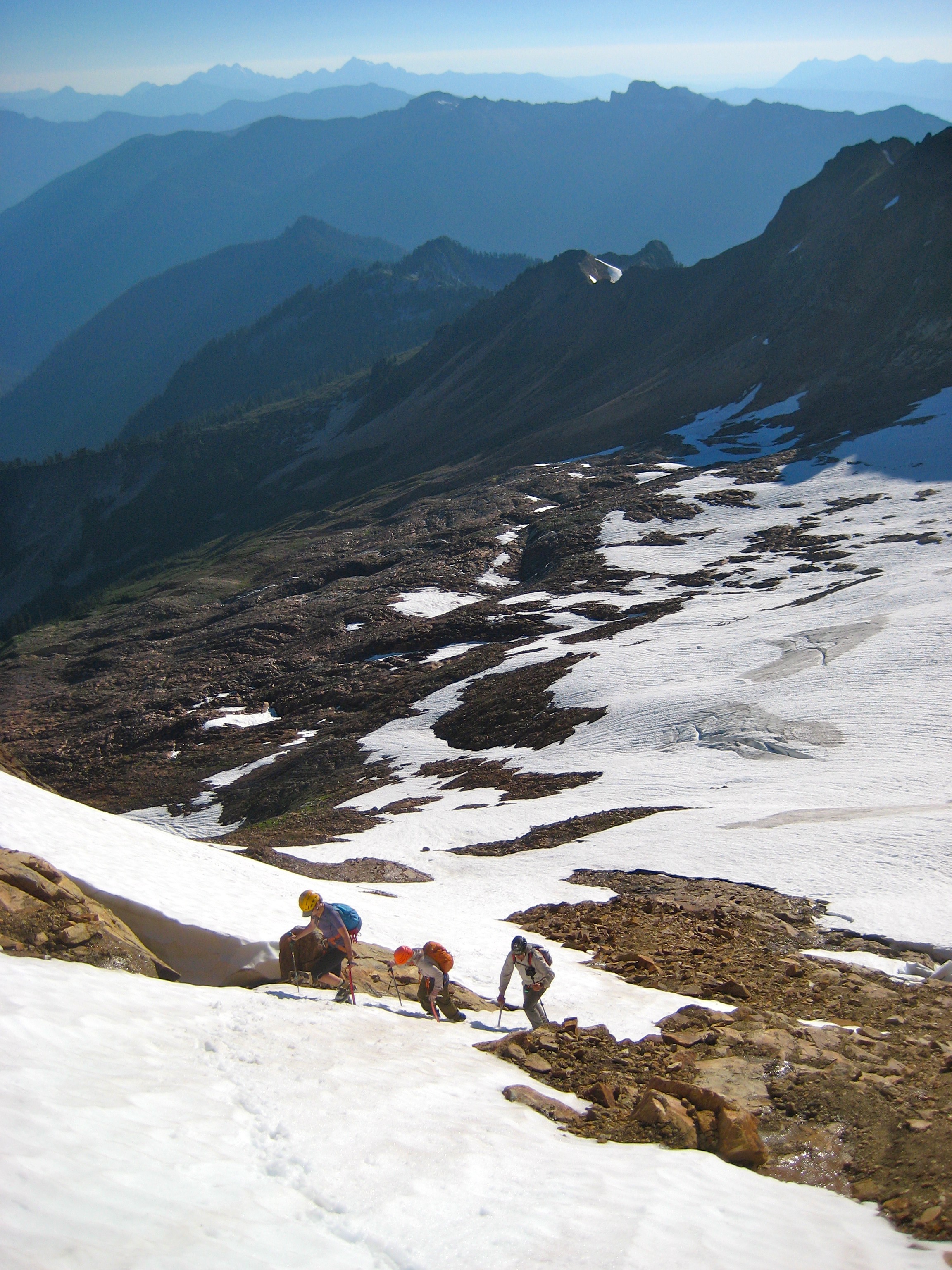 mountain climbers booting up snow finger on Mt Buckindy with snow fields and mountain ridges in the Glacier Peak WIlderness