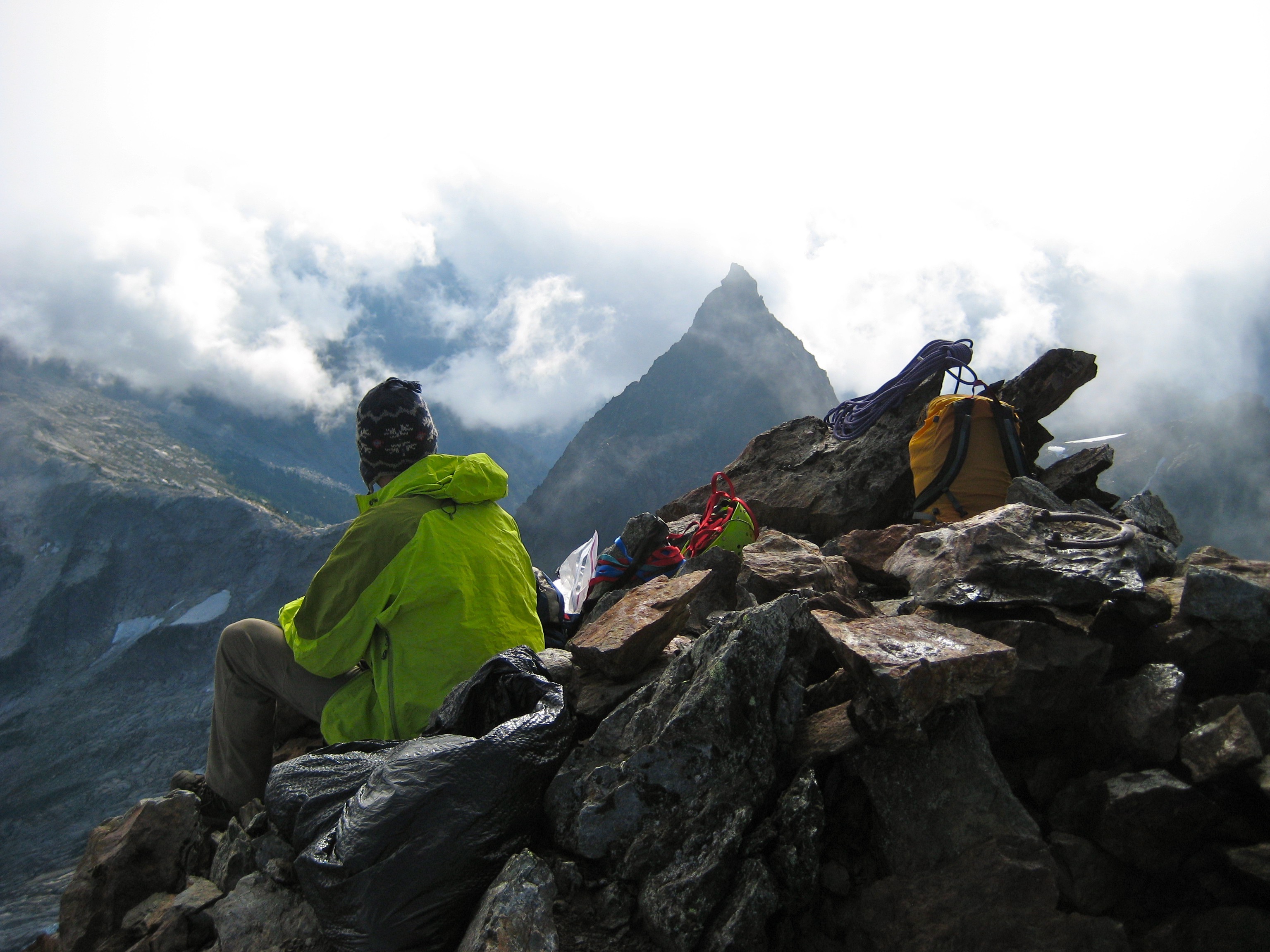 mountain climber sitting on the summit of Welch Peak in the Cheam Range with Foley Peak in the background