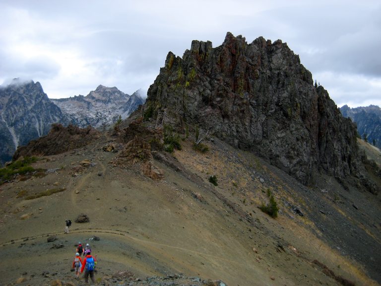 Hikers walk down a smooth ridge toward Volcanic Neck and Devils Head in the Teanaway Mountains