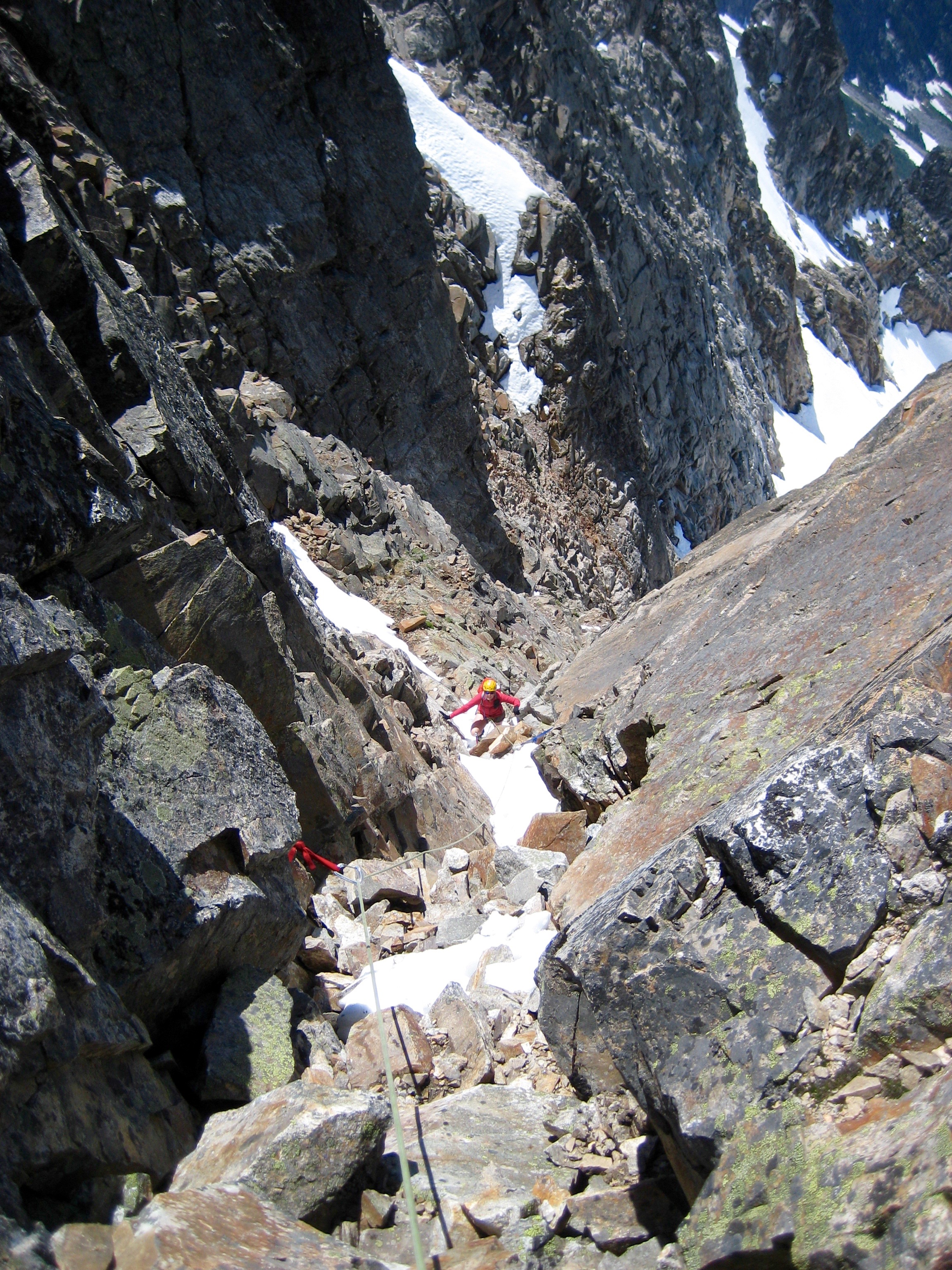 mountain climbers roped up transitioning from snow chute to rock scrambling heading for the Crooked Thumb Peak north ridge