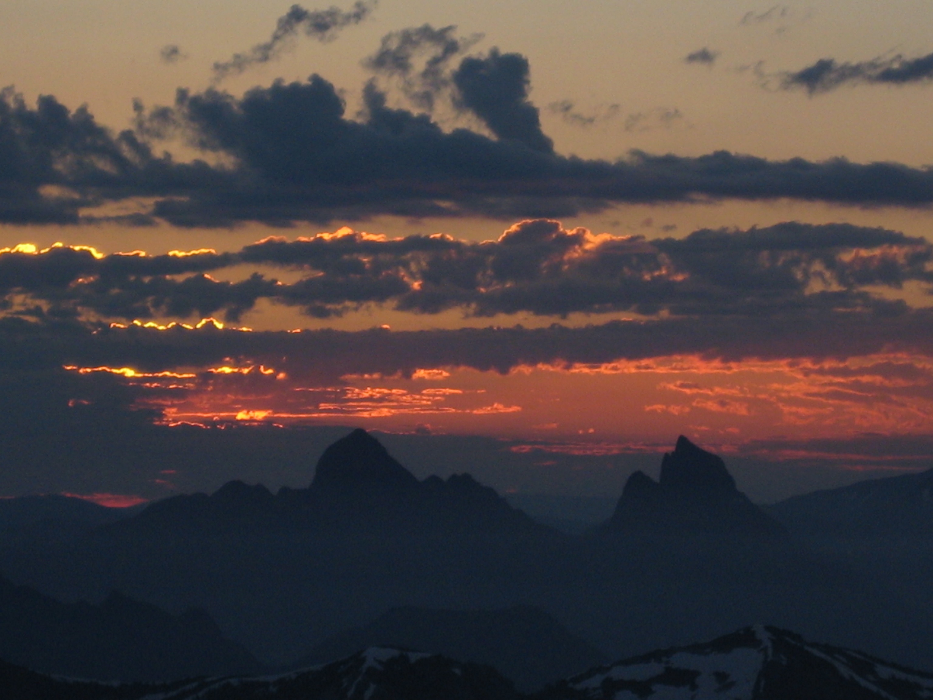 sunlight hitting clouds over Hozomeen Mountains from mountain climbers bivouac on the ridge of Crooked Thumb Peak