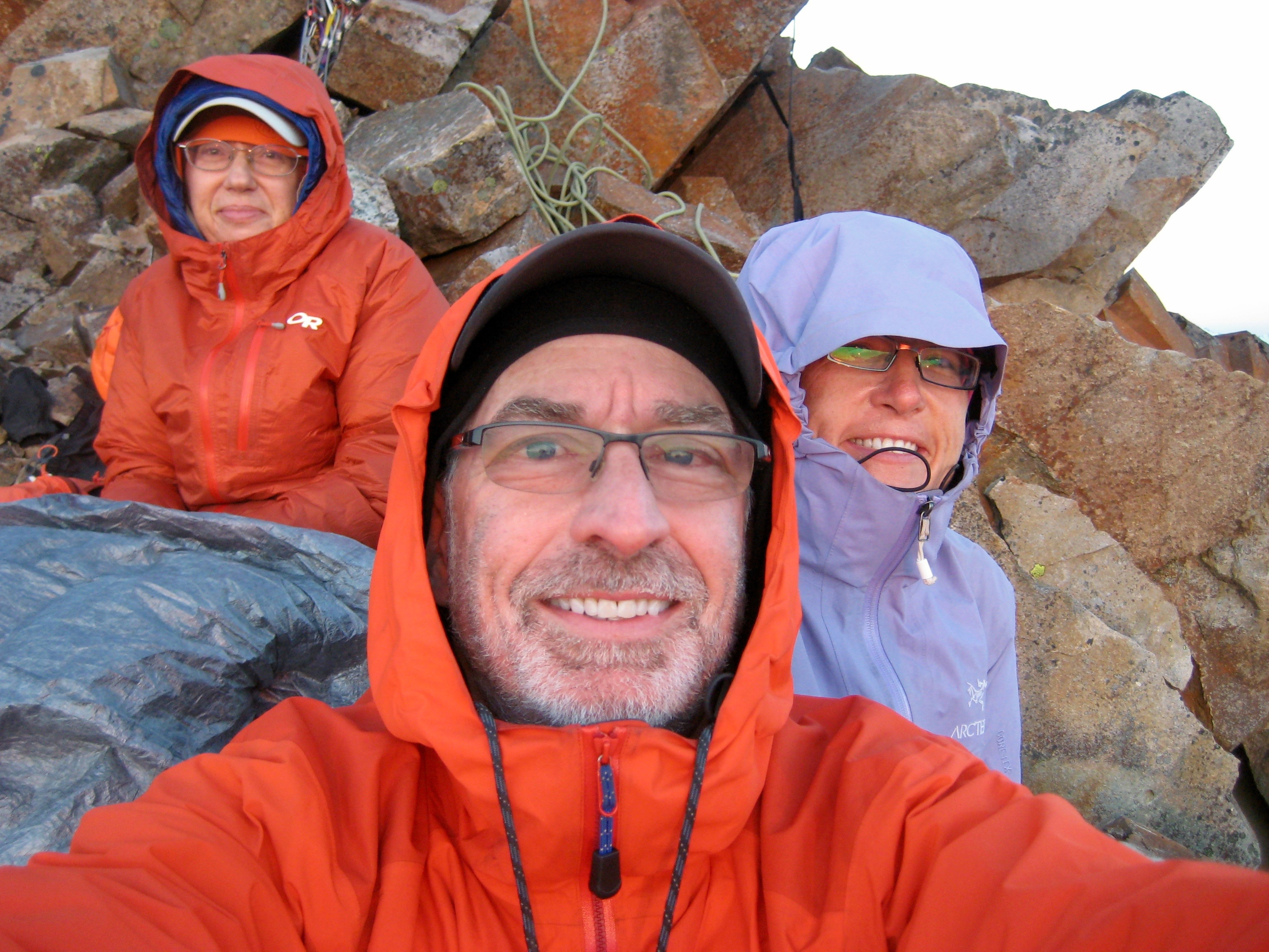 mountain climbers sitting in the rocks on the west ridge of Crooked Thumb Peak after a cold night bivouac