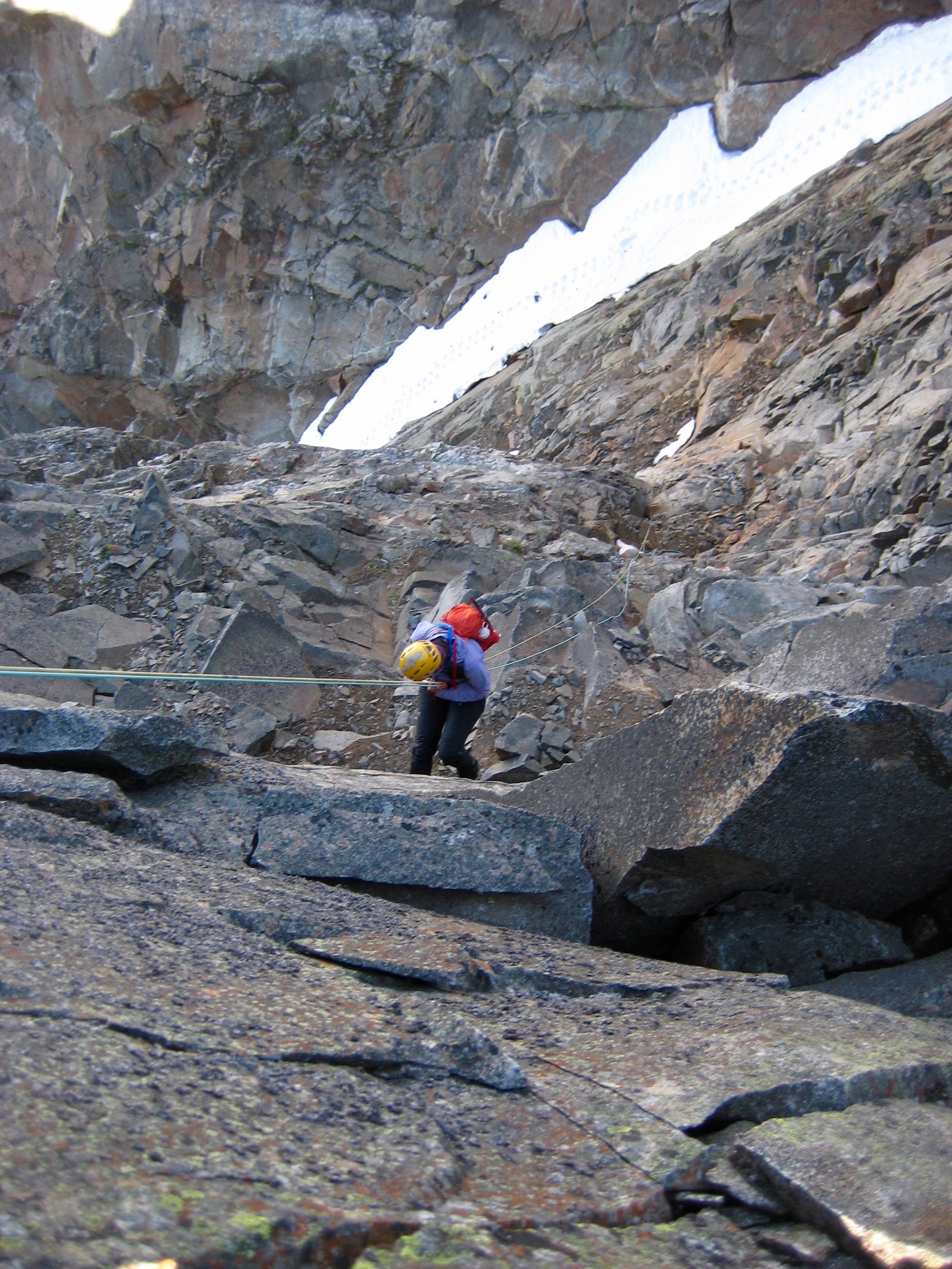 mountain climbers rappelling rock ledge on the west ridge of Crooked Thumb Peak heading for the snow couloir