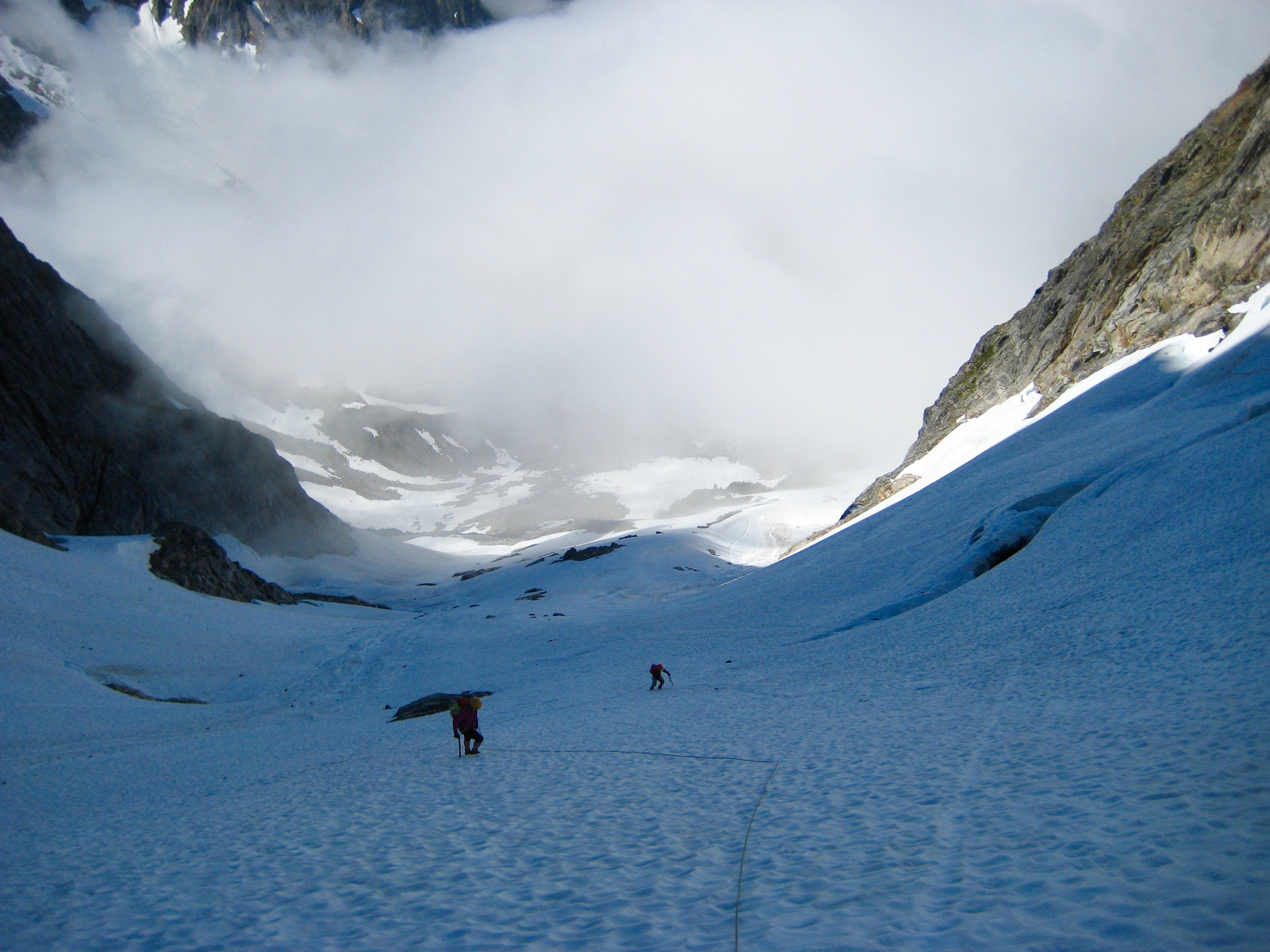 roped mountain climbers climbing snow slope heading toward bergschrund on the approach to Phantom Peak