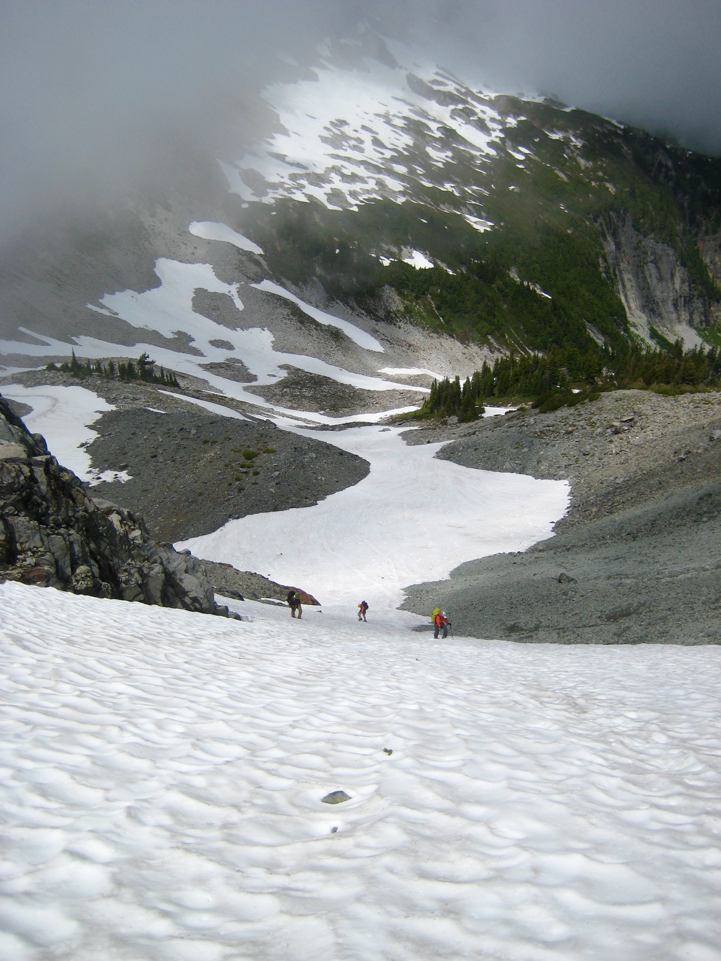 climbers booting up Unicorn snow couloir with cloud layer