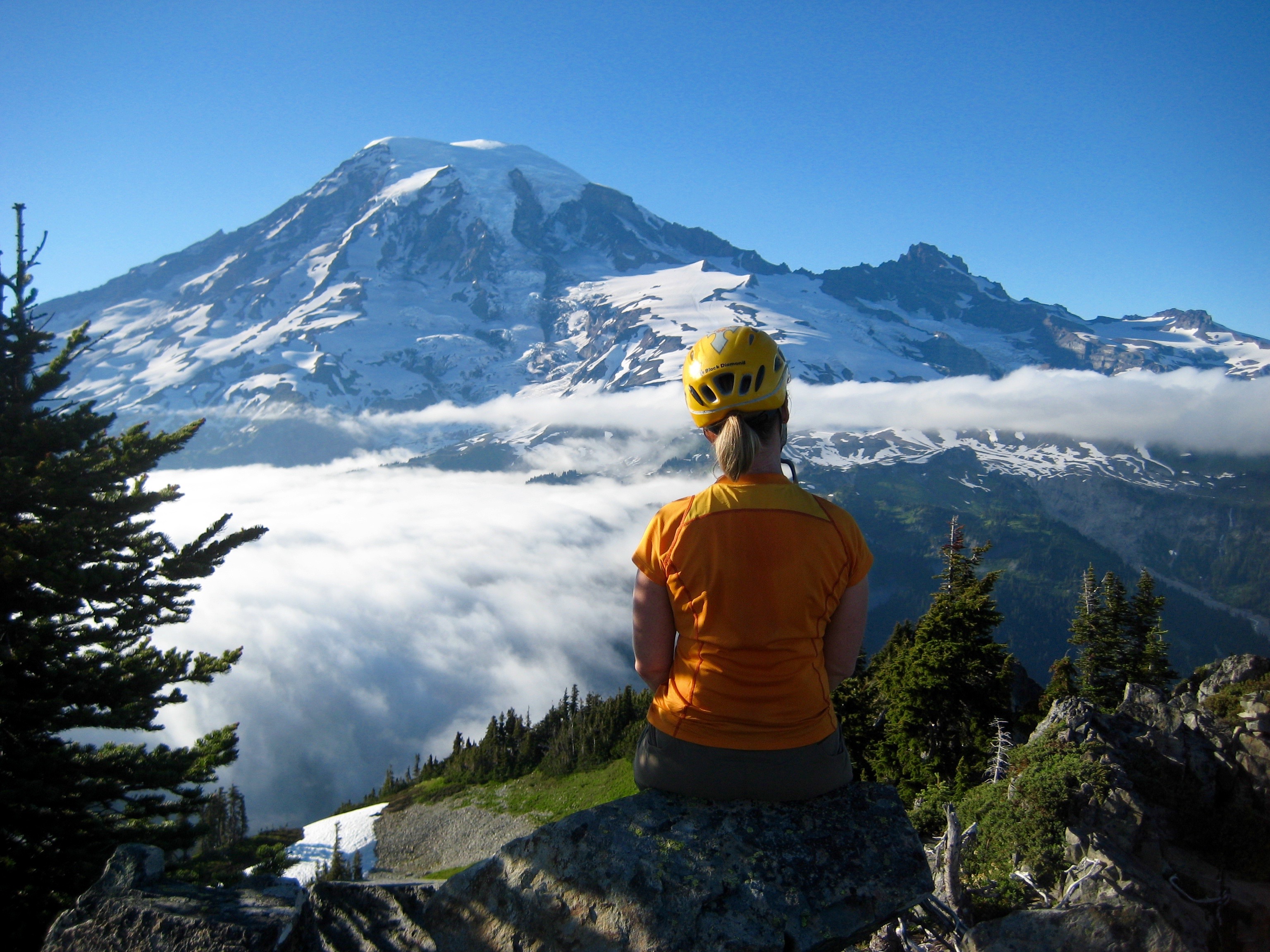 climber sitting on the summit of Thea Foss Peak looking at Mt Rainier