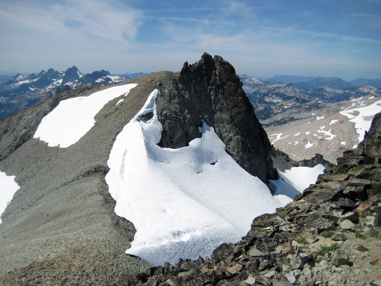 Jagged summit of West Peak of Mt Daniel with a gental scree approach and lingering snow patches