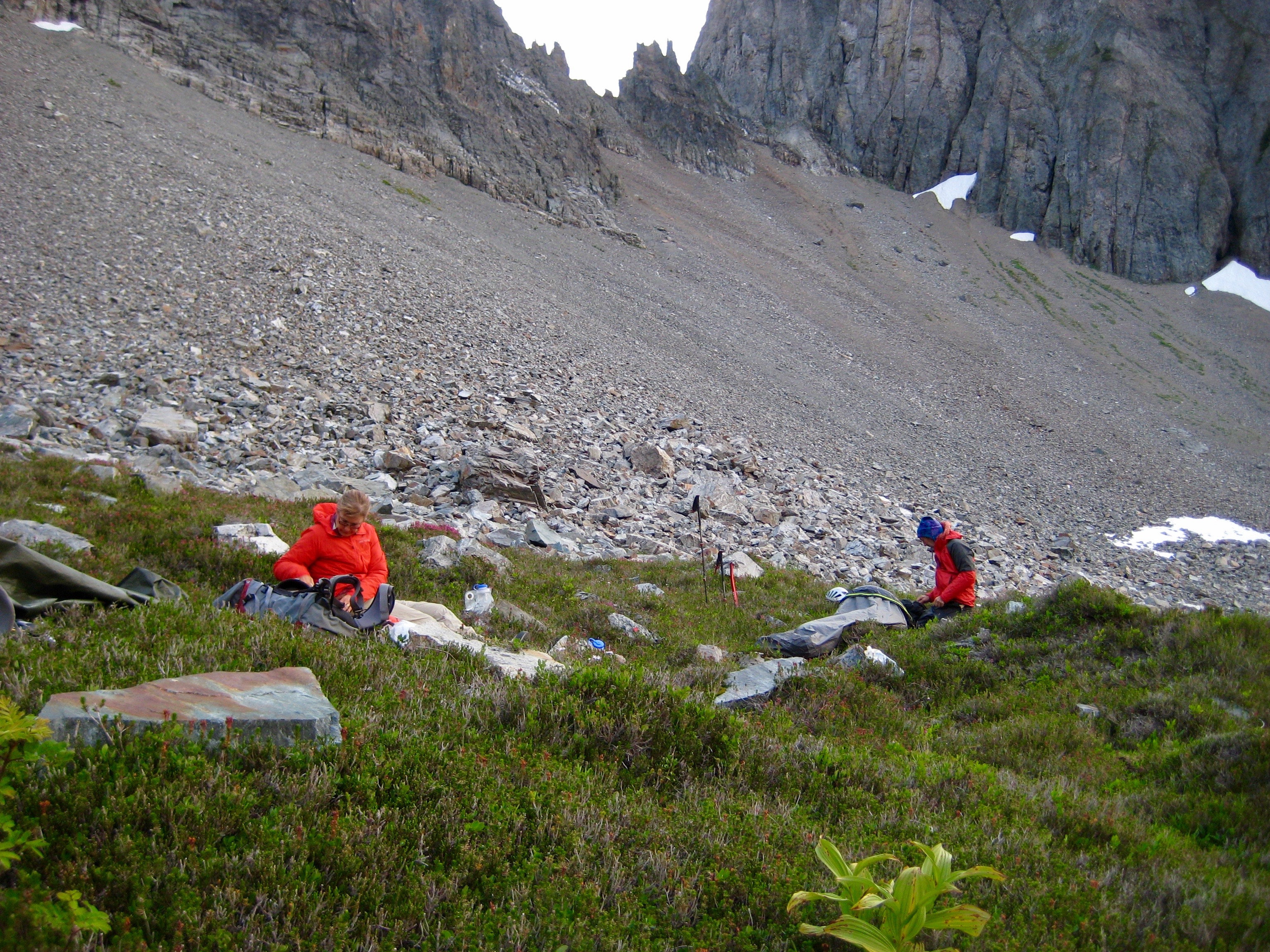 mountain climbers relaxing in heather camp with random large boulders and a large scree field in the background heading to notch below Johannesburg Mountain in North Cascades National Park