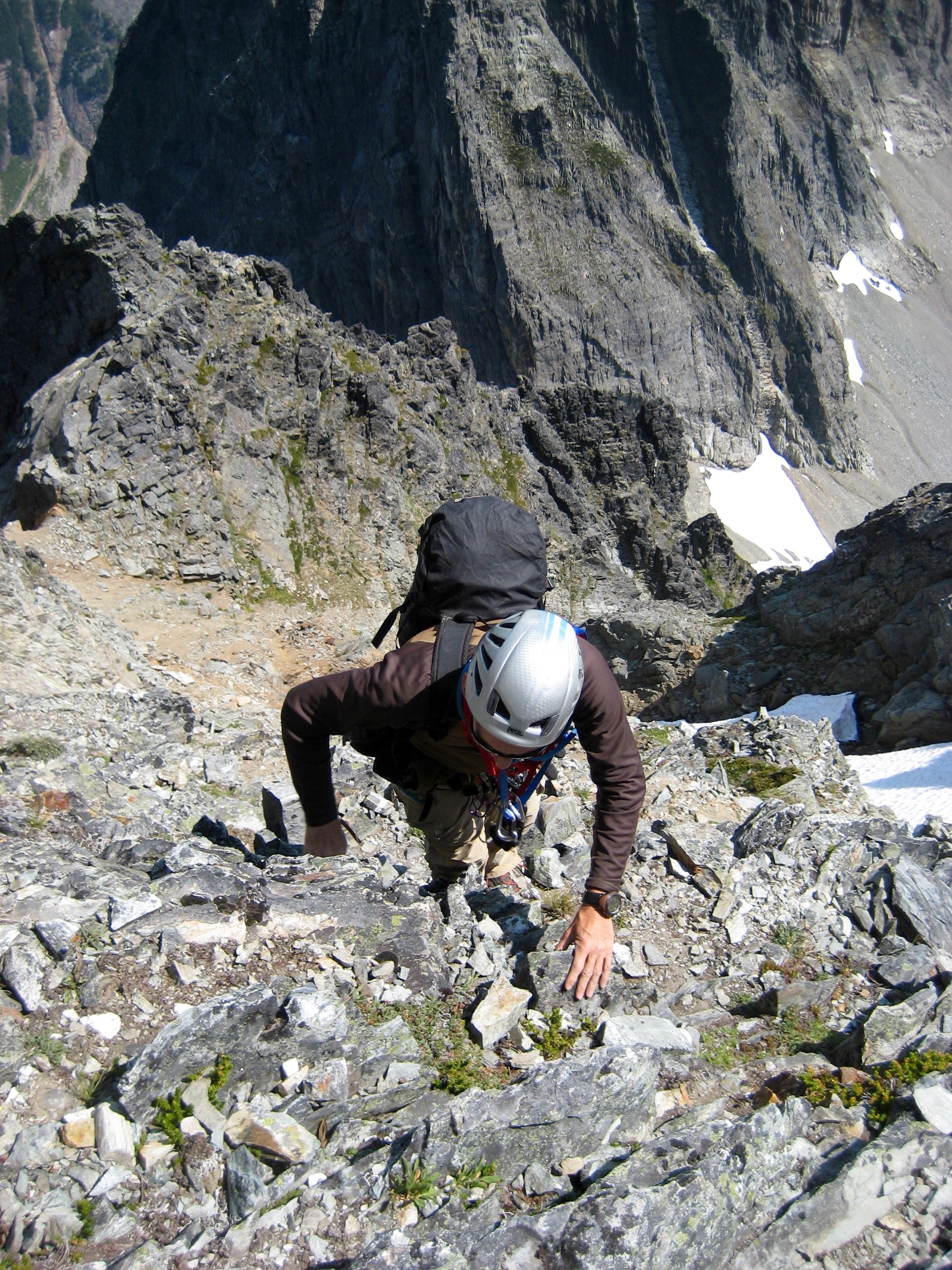looking down at mountain climber scrambling steep, loose rocky gully leading to the false summit of Johannesburg Mountain in the North Cascades National Park