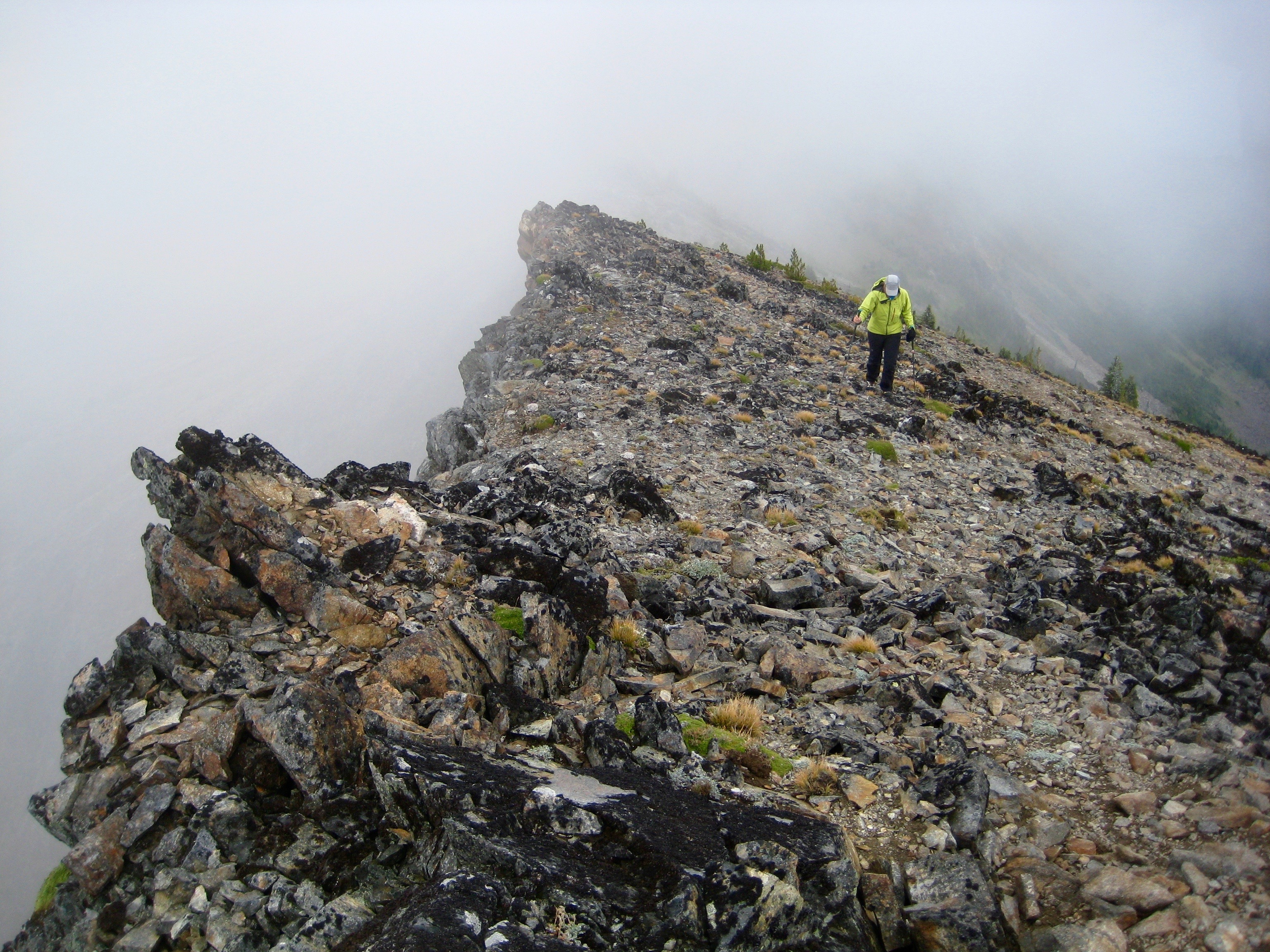 mountain climber hiking the rocky ridge of McWaukum Peak in the Chiwaukum Mountains with fog rolling over the ridge crest