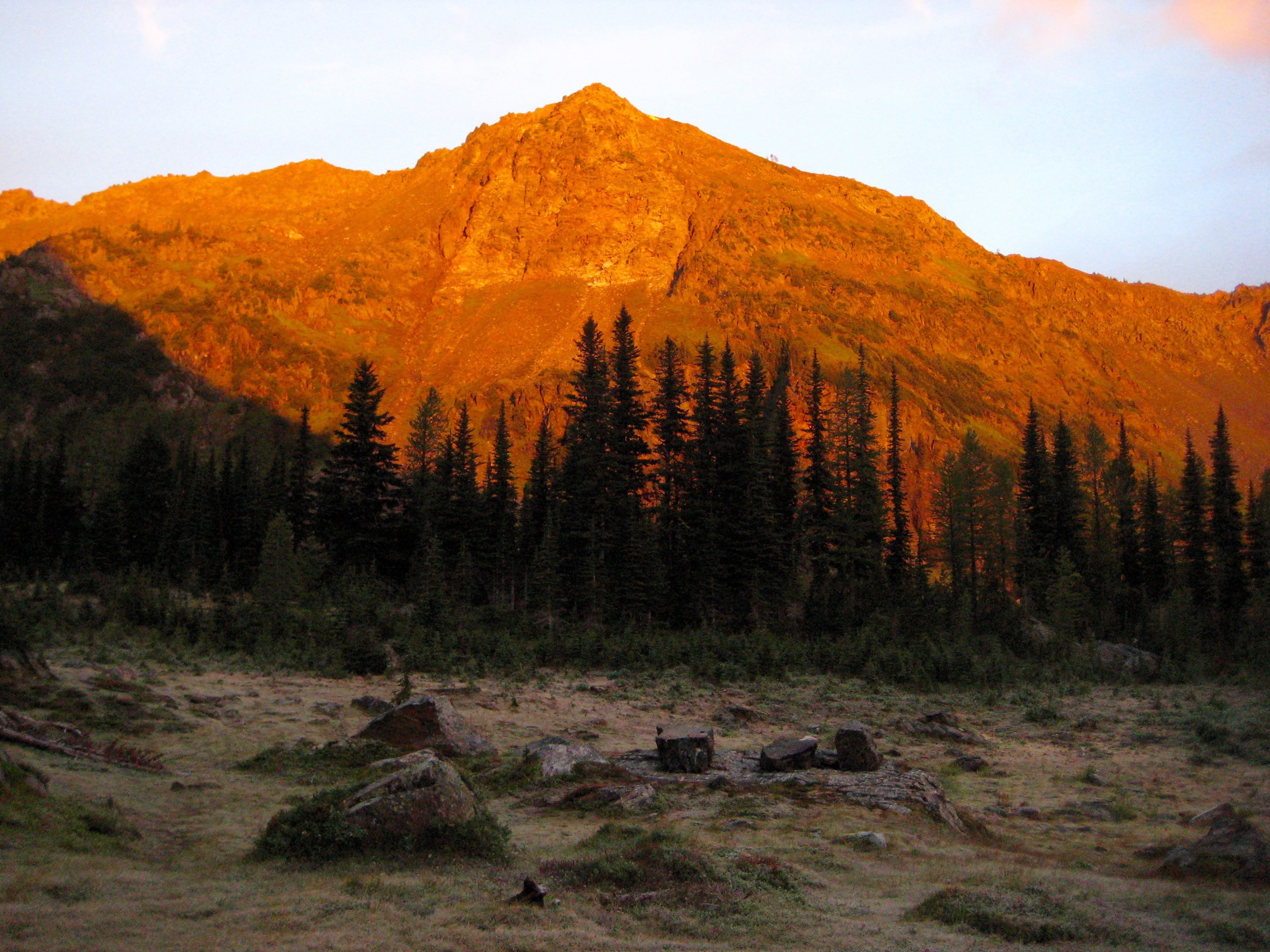 Alpenglow on Deadhorse Peak in the Chiwaukum Mountains with a grassy, boulder field in the foreground in the Alpine Lakes Wilderness