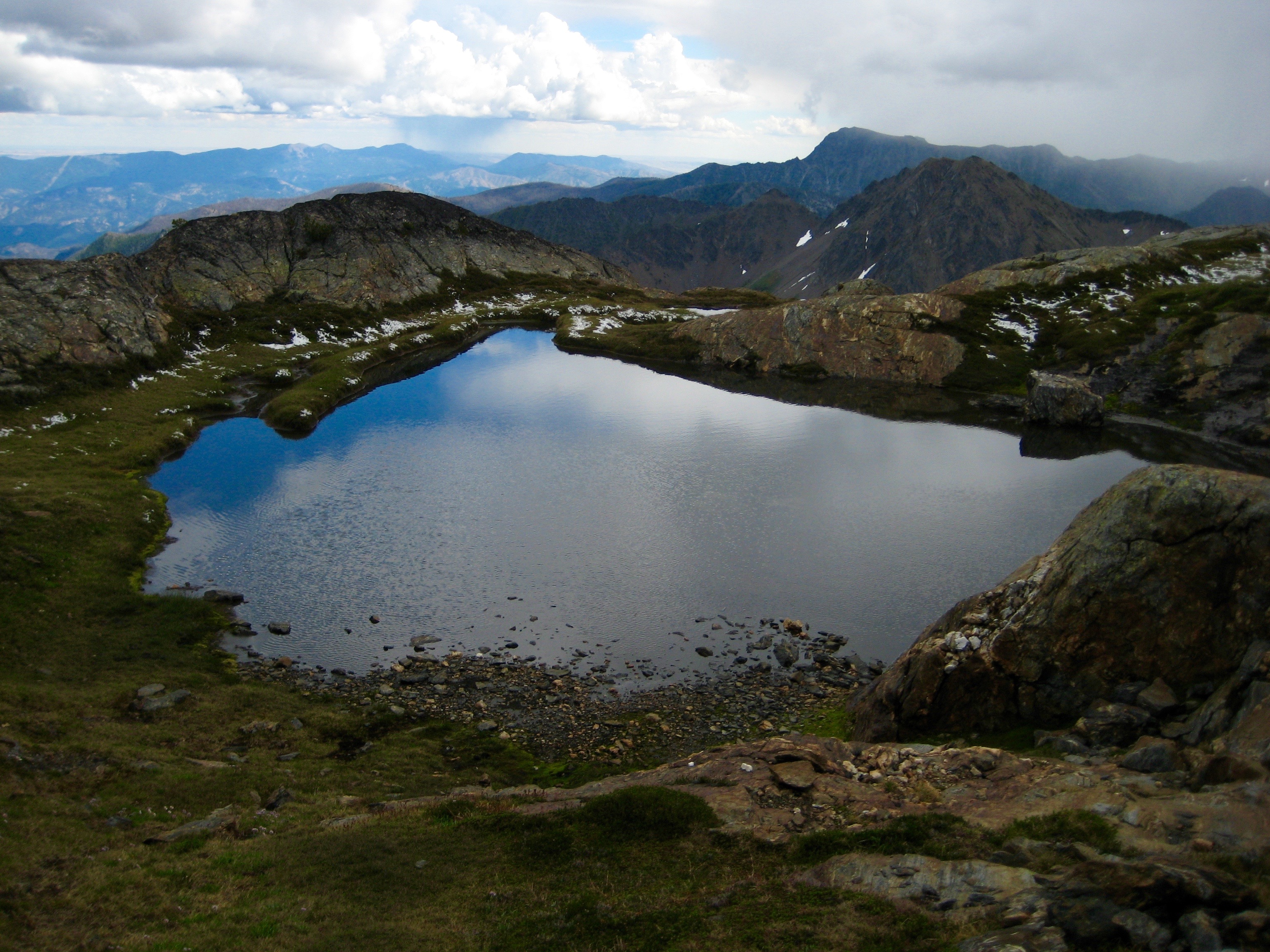 Tarn high in the Chiwaukum Mountains surrounded by a rocky shore below Big Chiwaukum Peak in the Alpine Lakes Wilderness