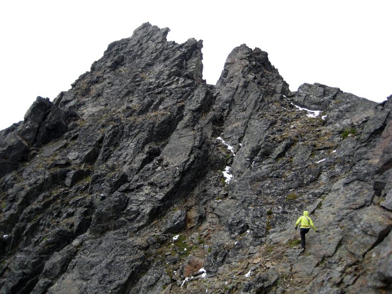 A lone mountain climber scrambles toward the craggy summit of Big Chiwaukum Peak in the Alpine Lakes Wilderness