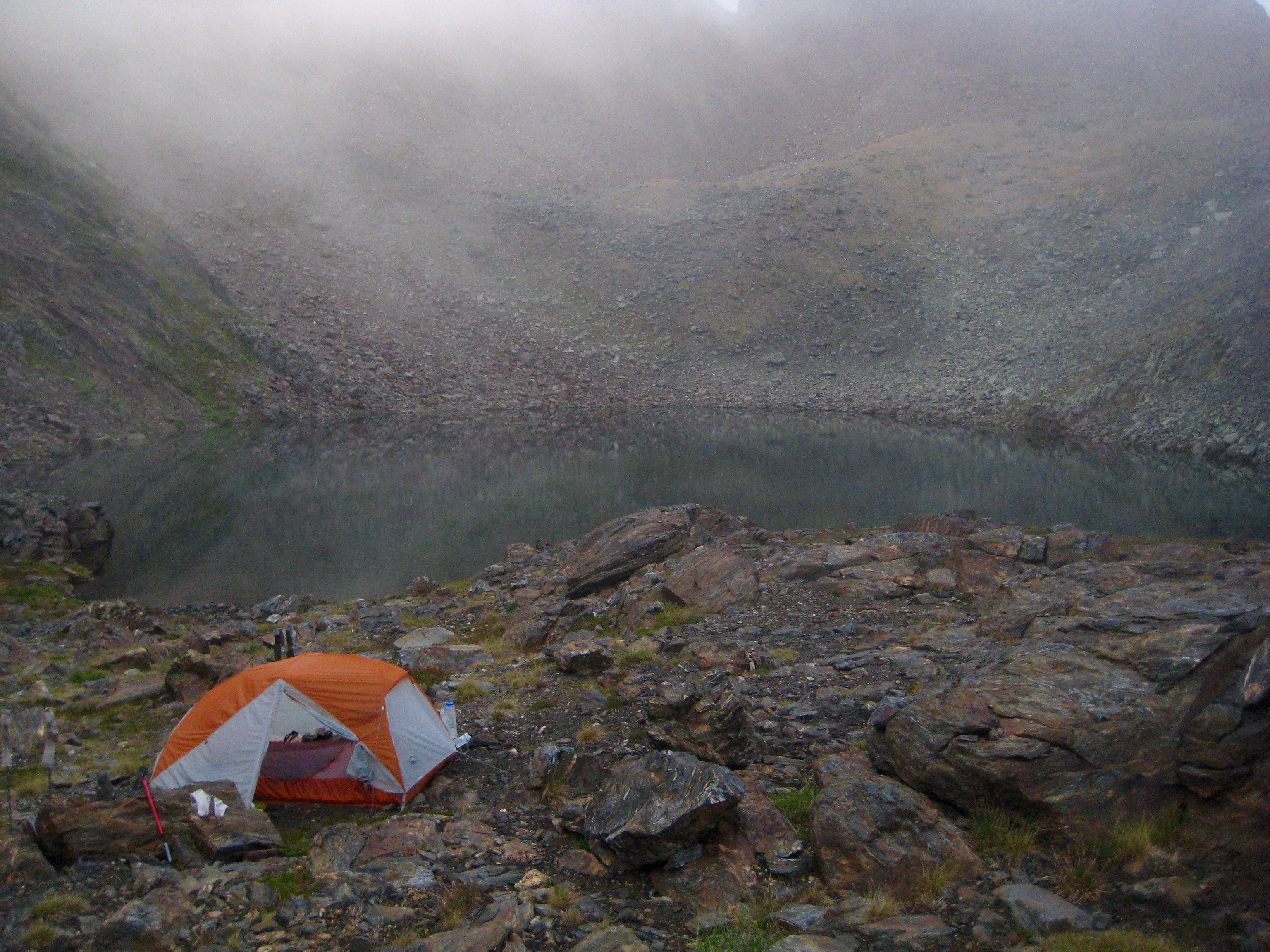 mountain climber camp on rocky slab next to Upper Grace Lake along the Chiwaukum Traverse in the Alpine Lakes Wilderness