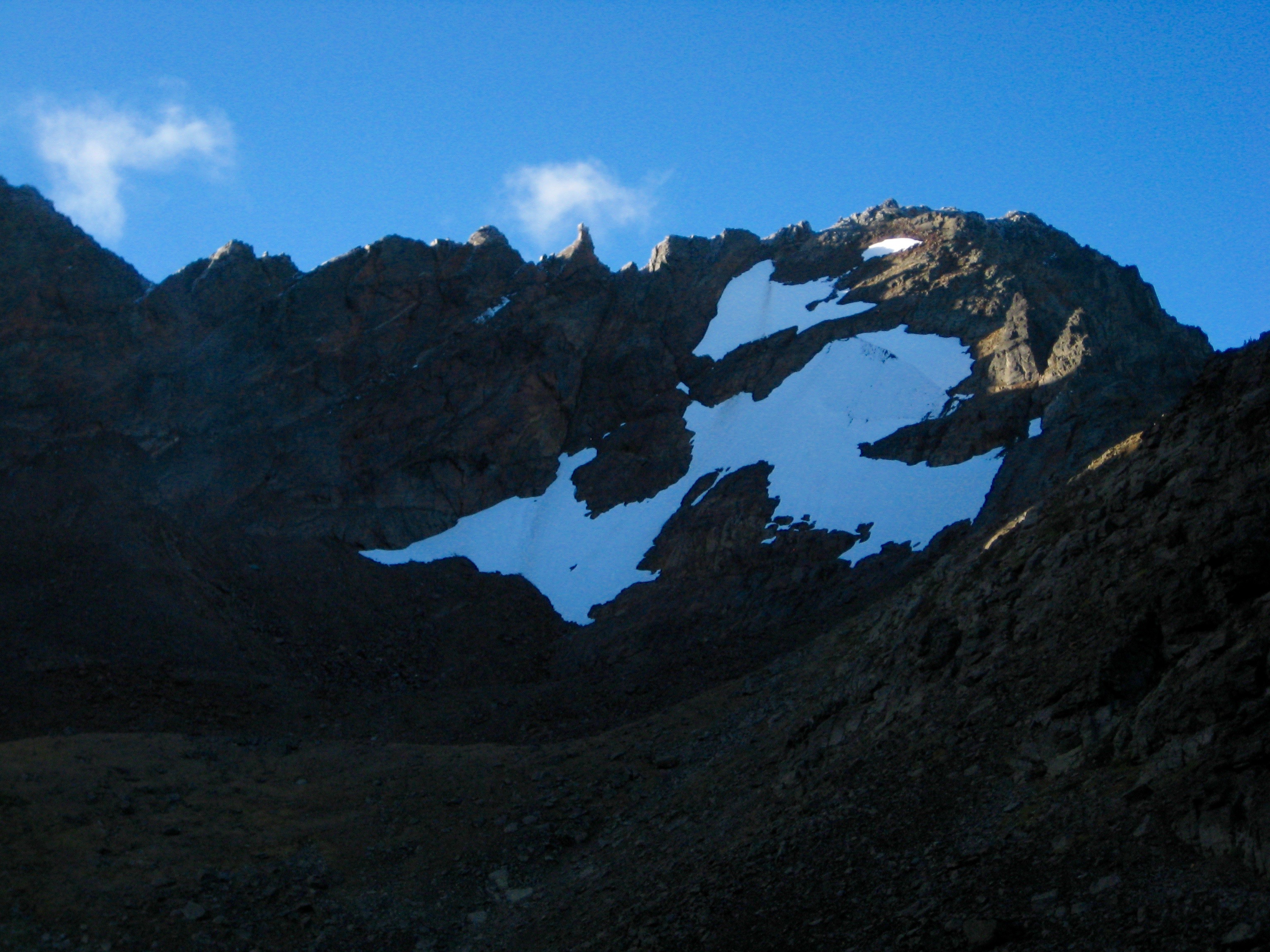 Snowgrass Mountain with linguring snow patched and blue skies as seen from Upper Grace Lake climbers camp in the Chiwaukum Mountains in the Alpine Lakes Wilderness