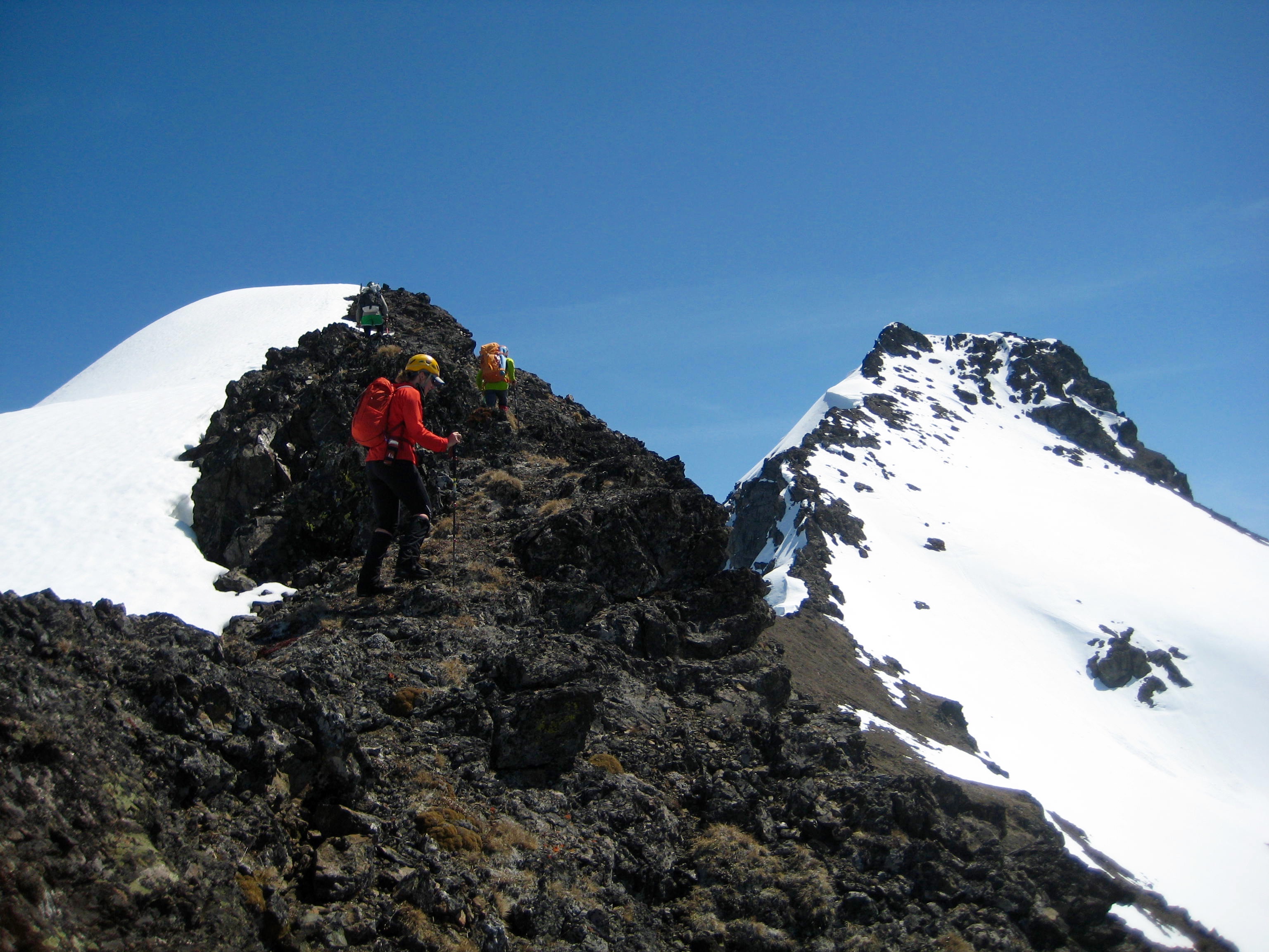 mountain climbers scrambling over the false summit of Silvertip Mountain with the main summit block in the background