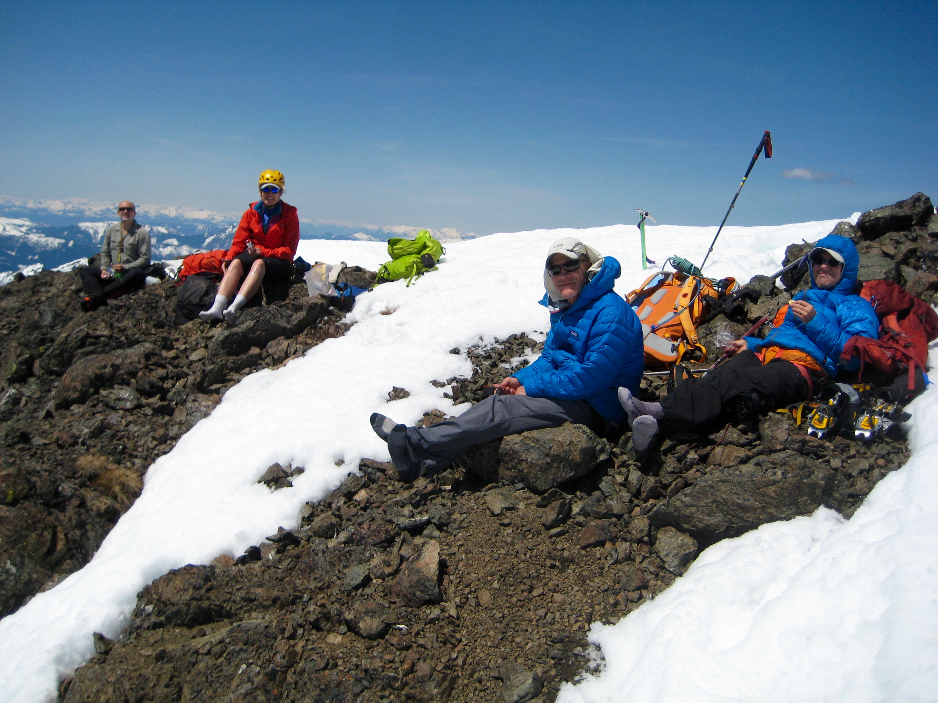 mountain climbers relaxing in the sun on the summit of SIlvertip Mountain with intermitten snow patches