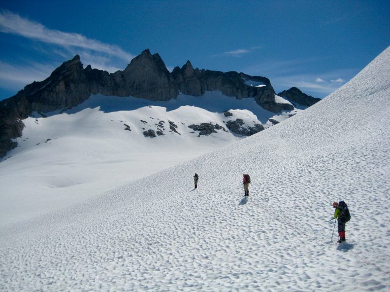 Three mountain climbers traverse Chikamin Glacier en route to Gunsight Peak in the Glacier Peak Wilderness