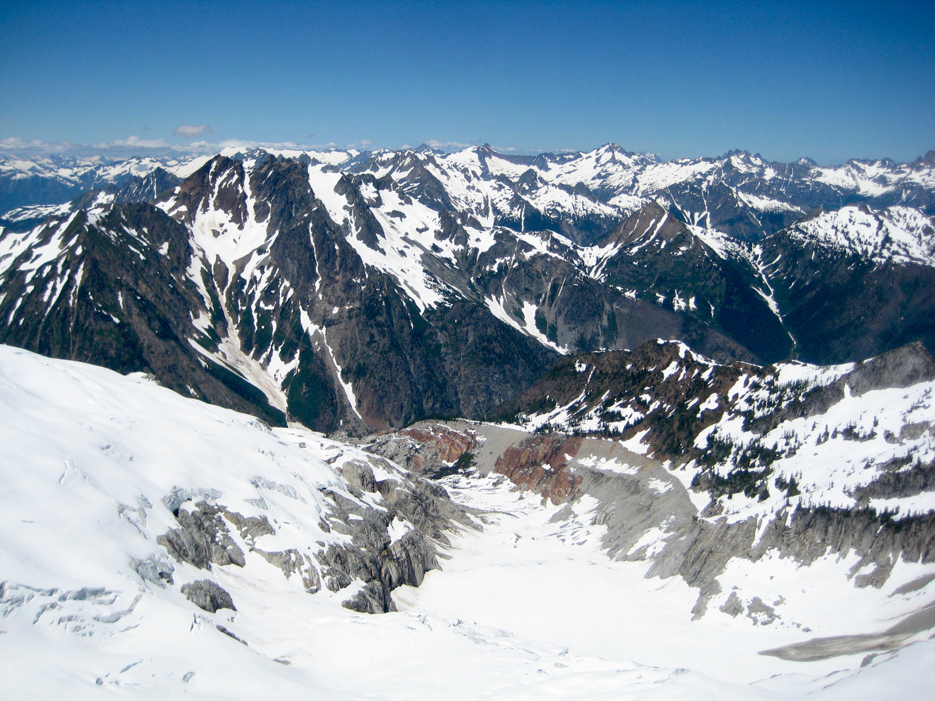 mountains of the Glacier Peak WIlderness with snow slopes as seen from the summit of SInister Peak in the Ptarmigan Mountains