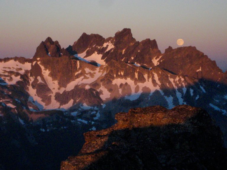 Evening sun warms the face of Chimney Rock as the moon rises over it as seen from the summit of Big Snow Mountain in the Miller-Foss Mountains