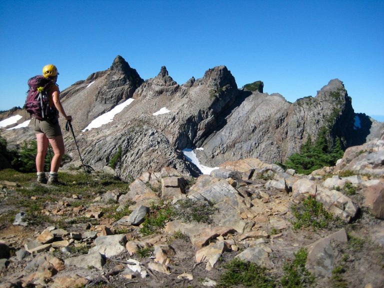 A mountain climber on Del Campo Peak studies the multiple summit horns of Gothic Peak in the Monte Cristo Mountains