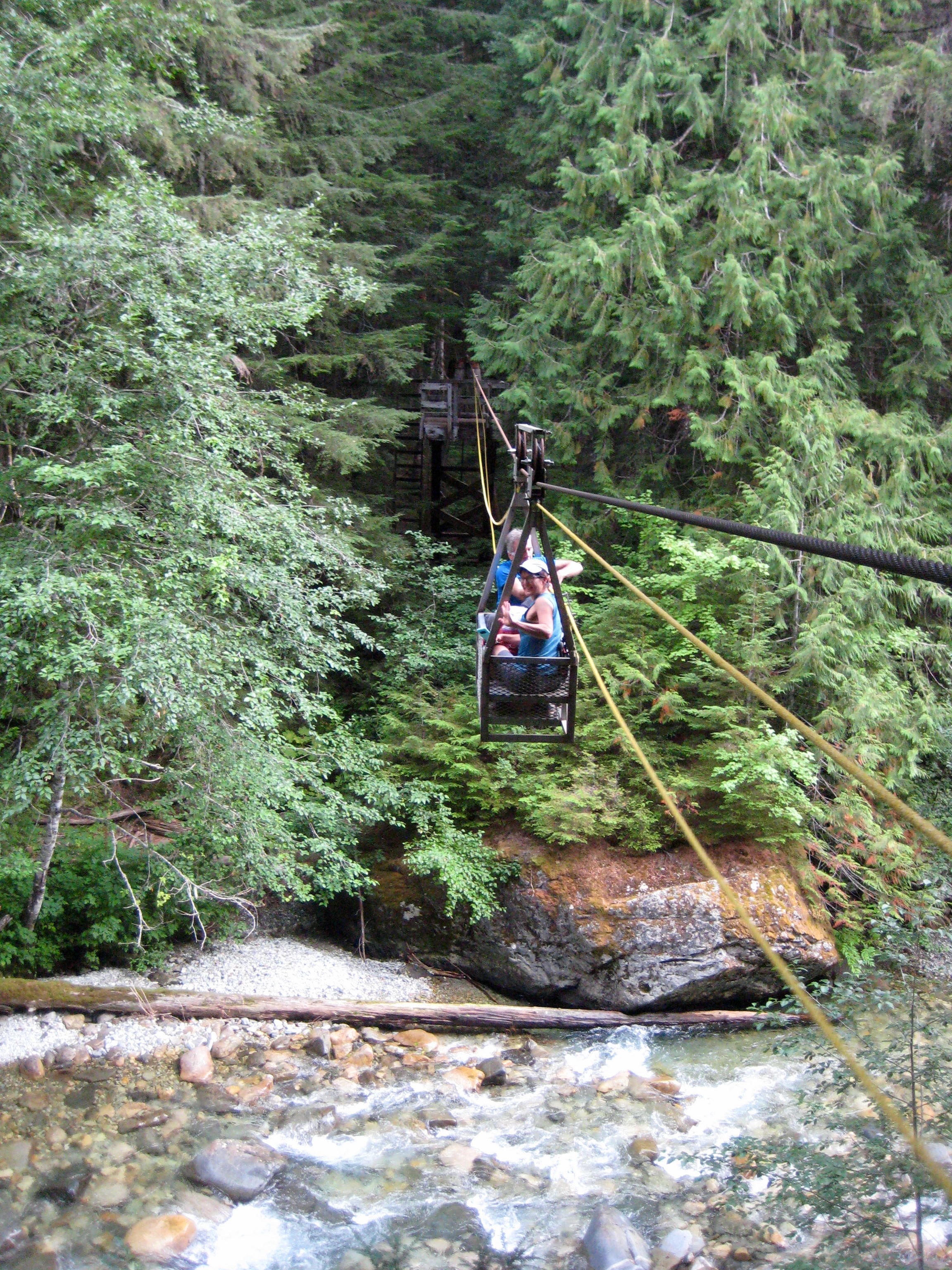 mountain climbers in the manual cable car over the chilliwack mountains with the forest in the background